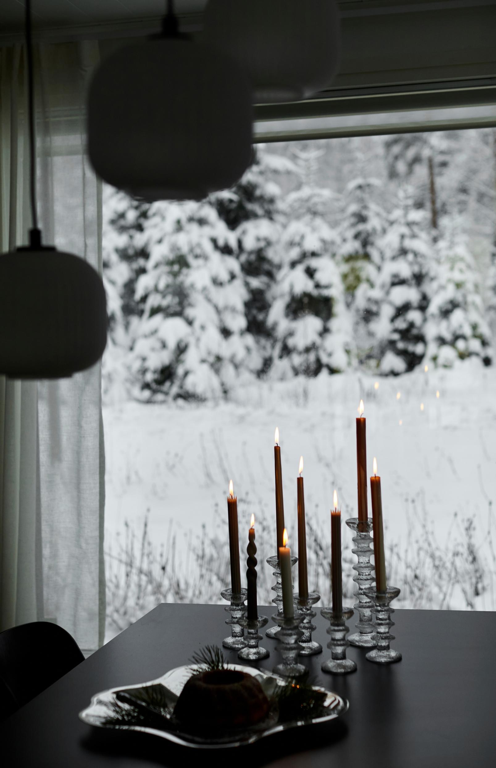 Ultima Thule candle holders, a metal tray, a black table, candles, and a snowy view