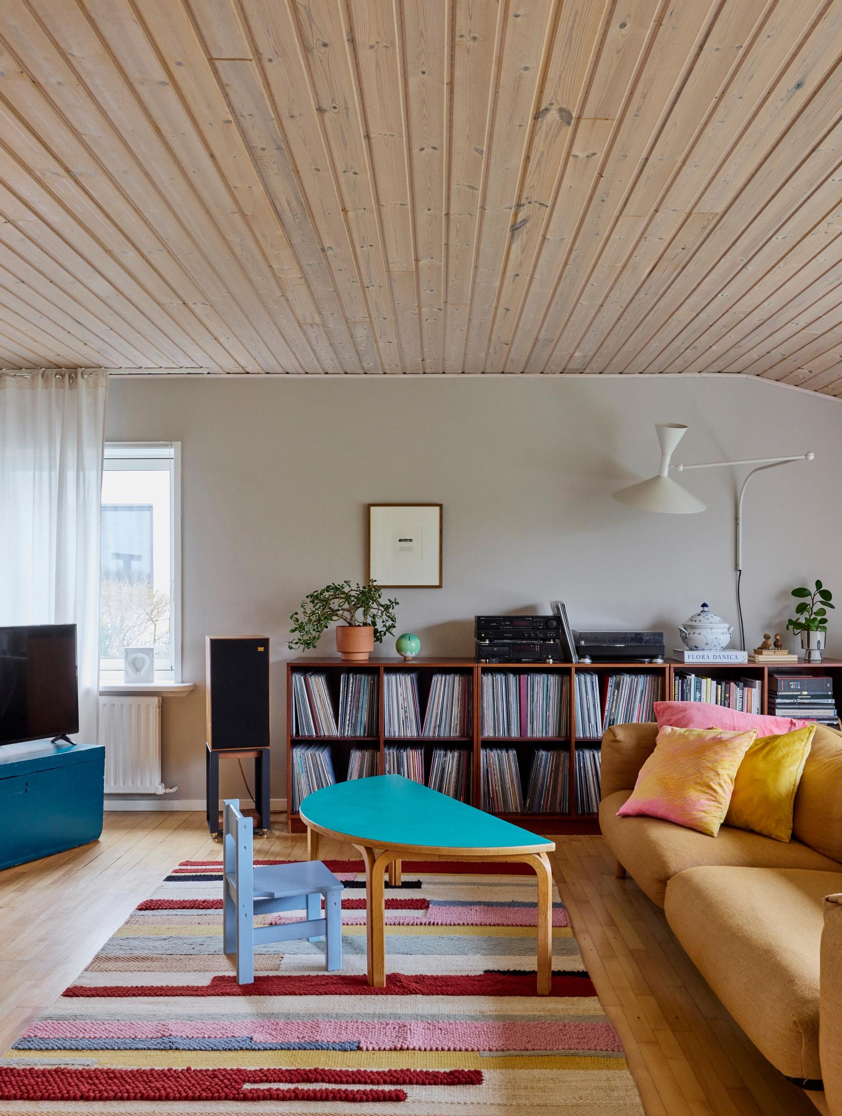 A striped wool rug, a laminate-topped table, and a wool-upholstered sofa in the living room.