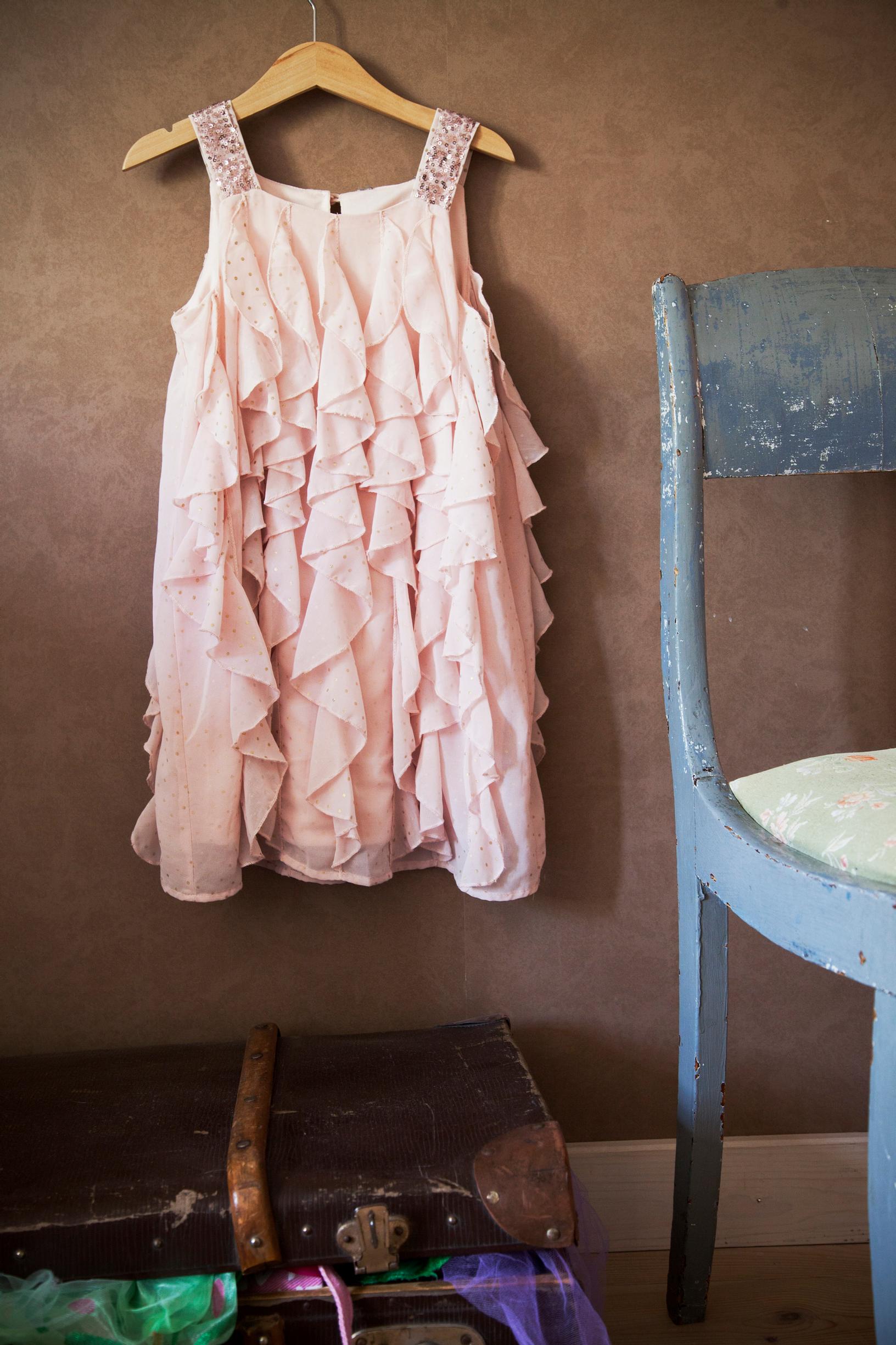 A pink dress hangs on the wall.