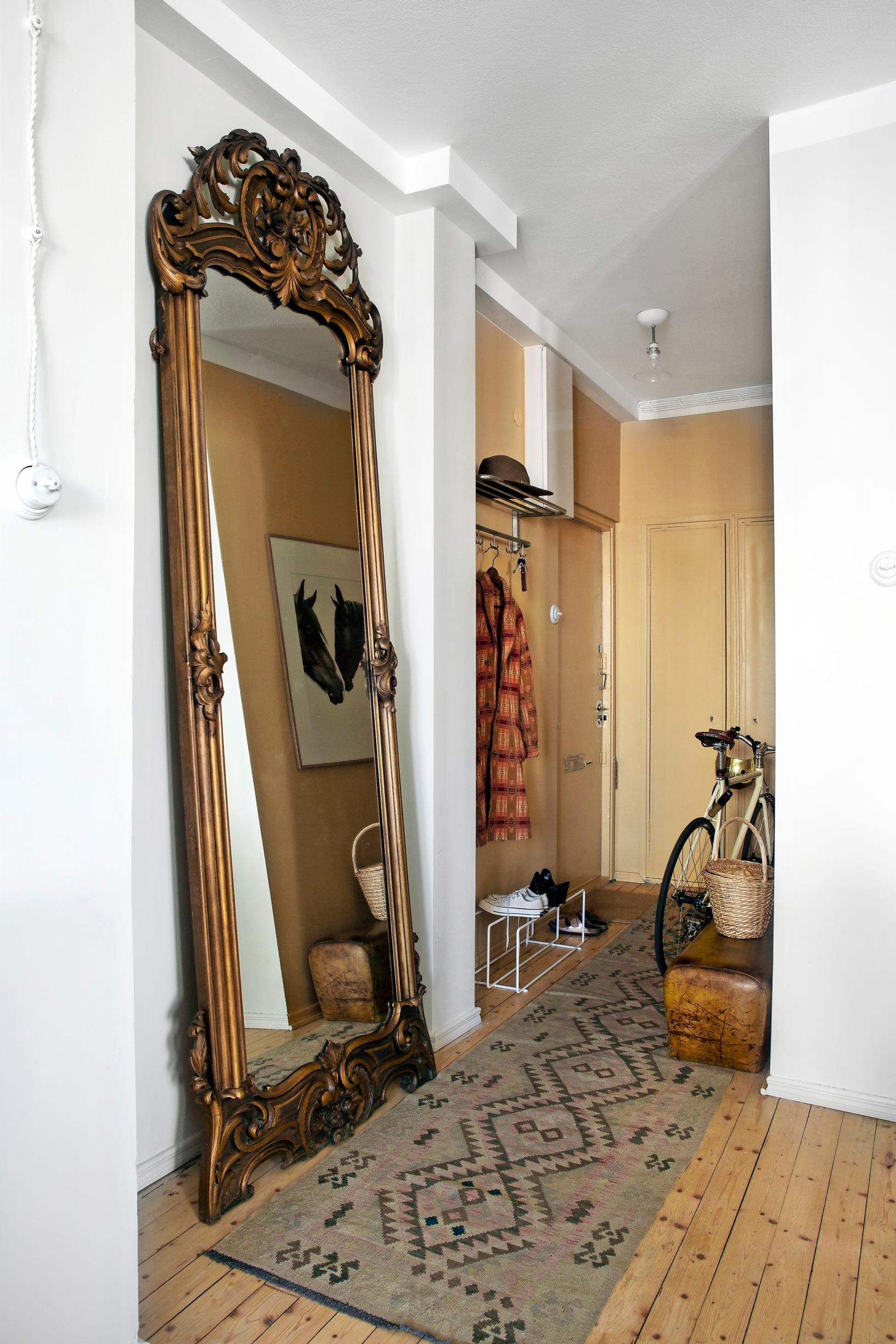 A large entryway mirror with a gilded and ornate frame