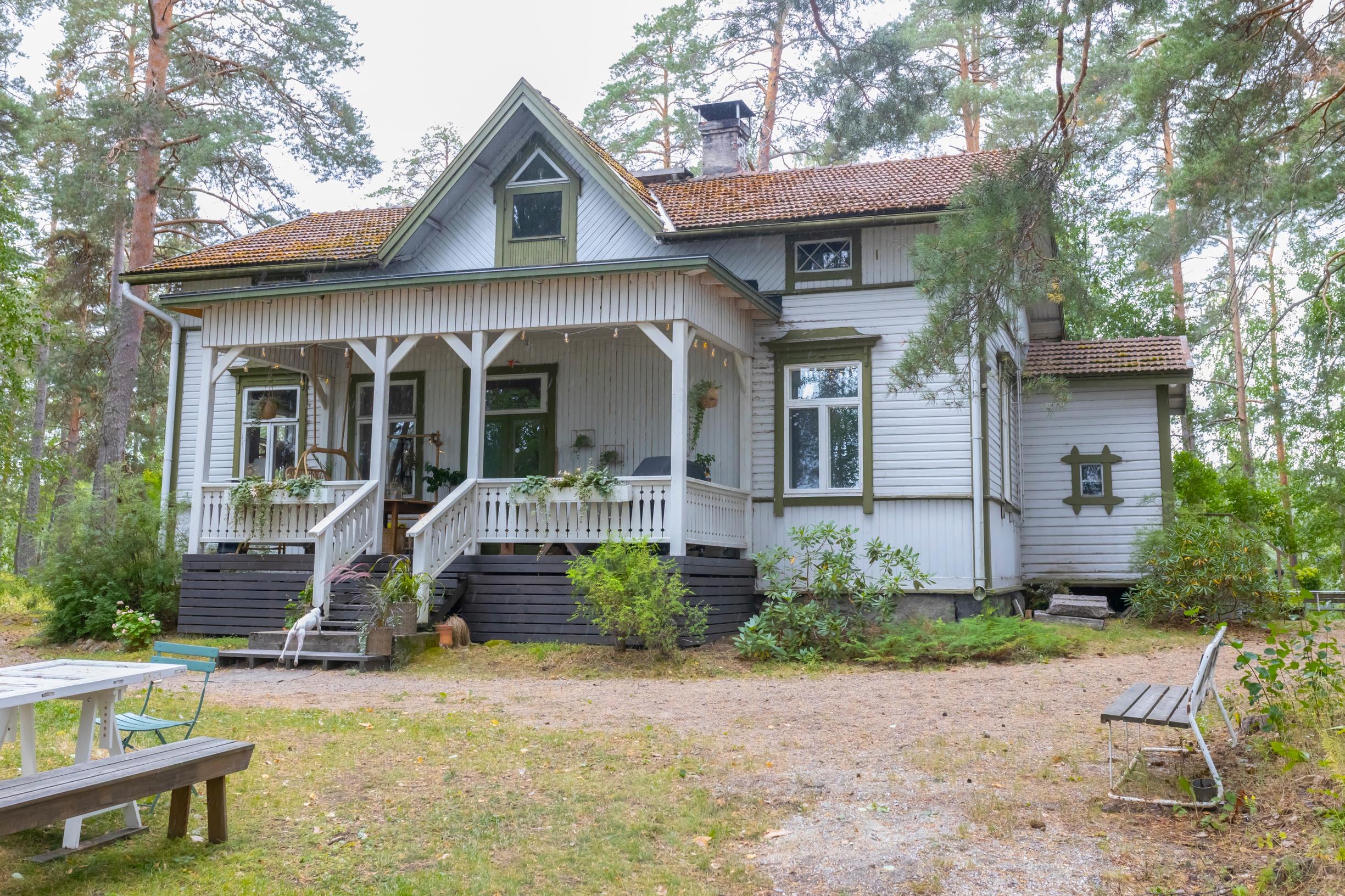 White wooden villa, red roof, and garden furniture in the garden.