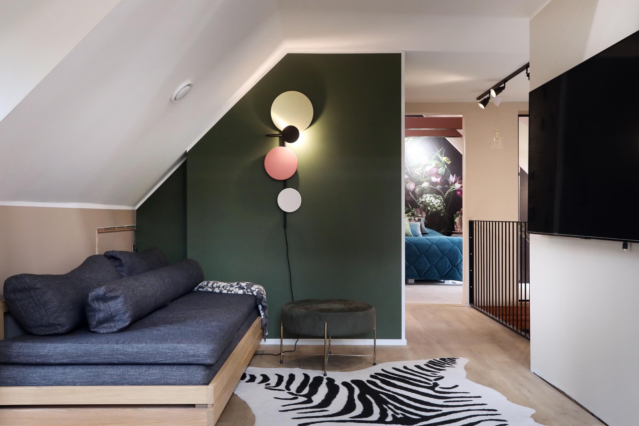 The landing features a green wall, a gray sofa bed, and a wall-mounted TV.