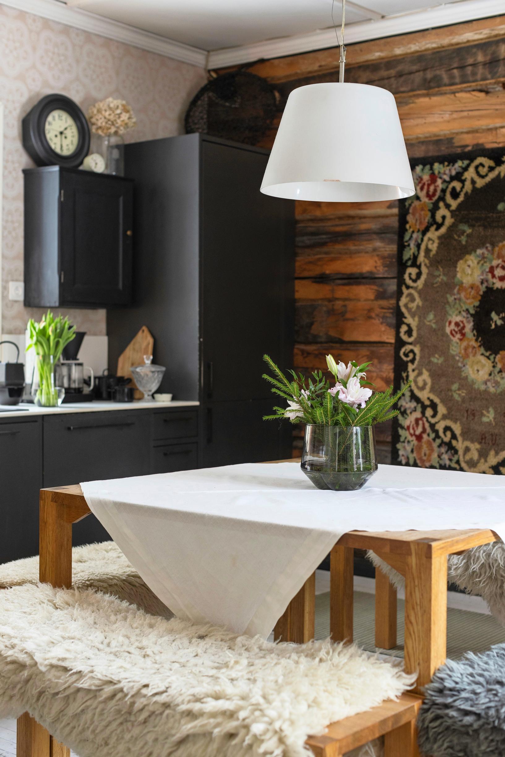 A black kitchen and dining table, featuring one bench that is higher.