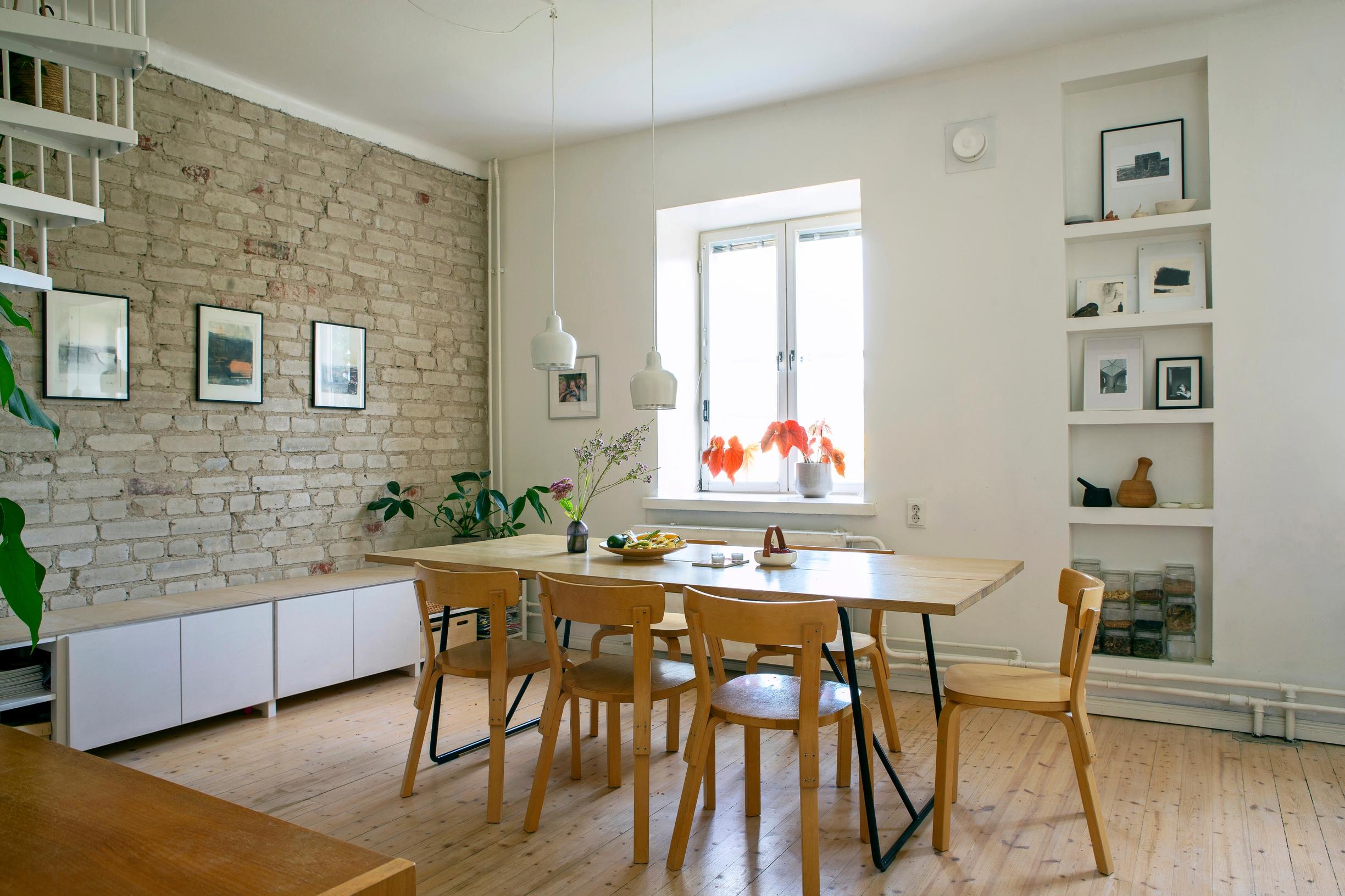 A brick wall on the left; a dining area occupies the center of the room.