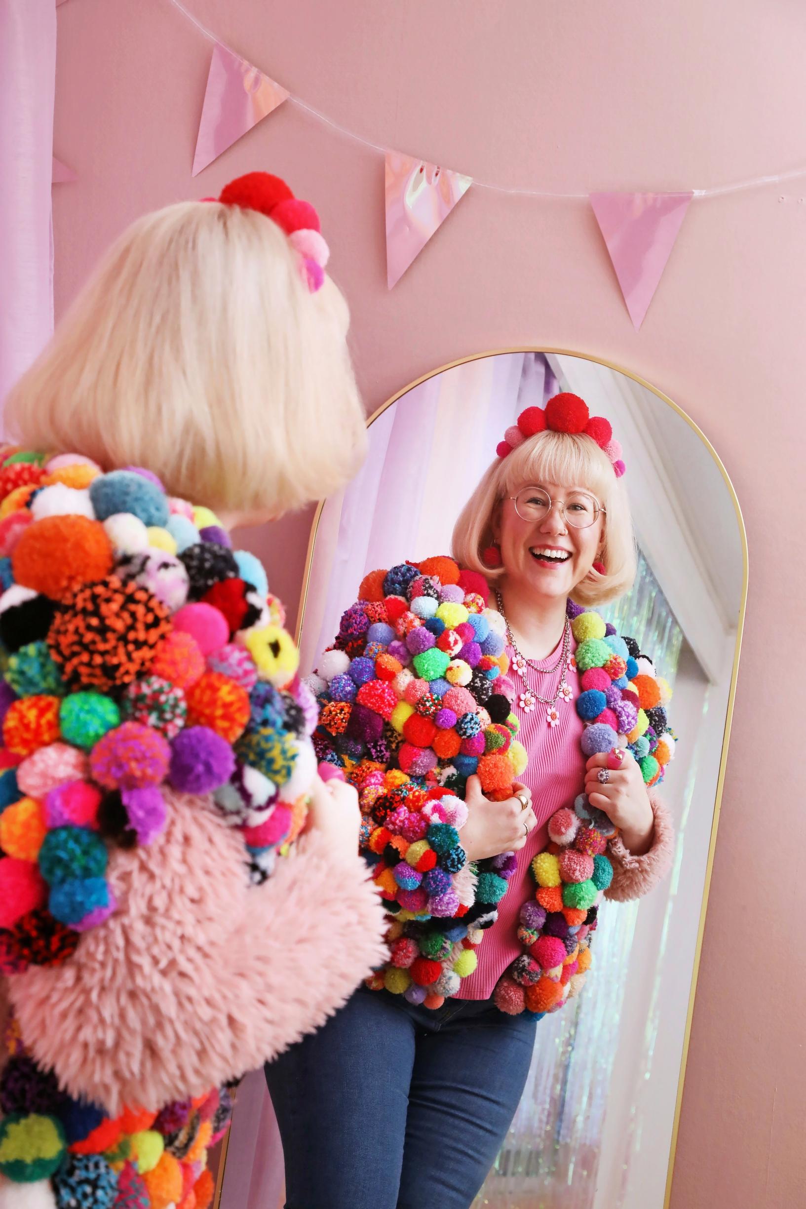 Mari wearing a pom-pom jacket.