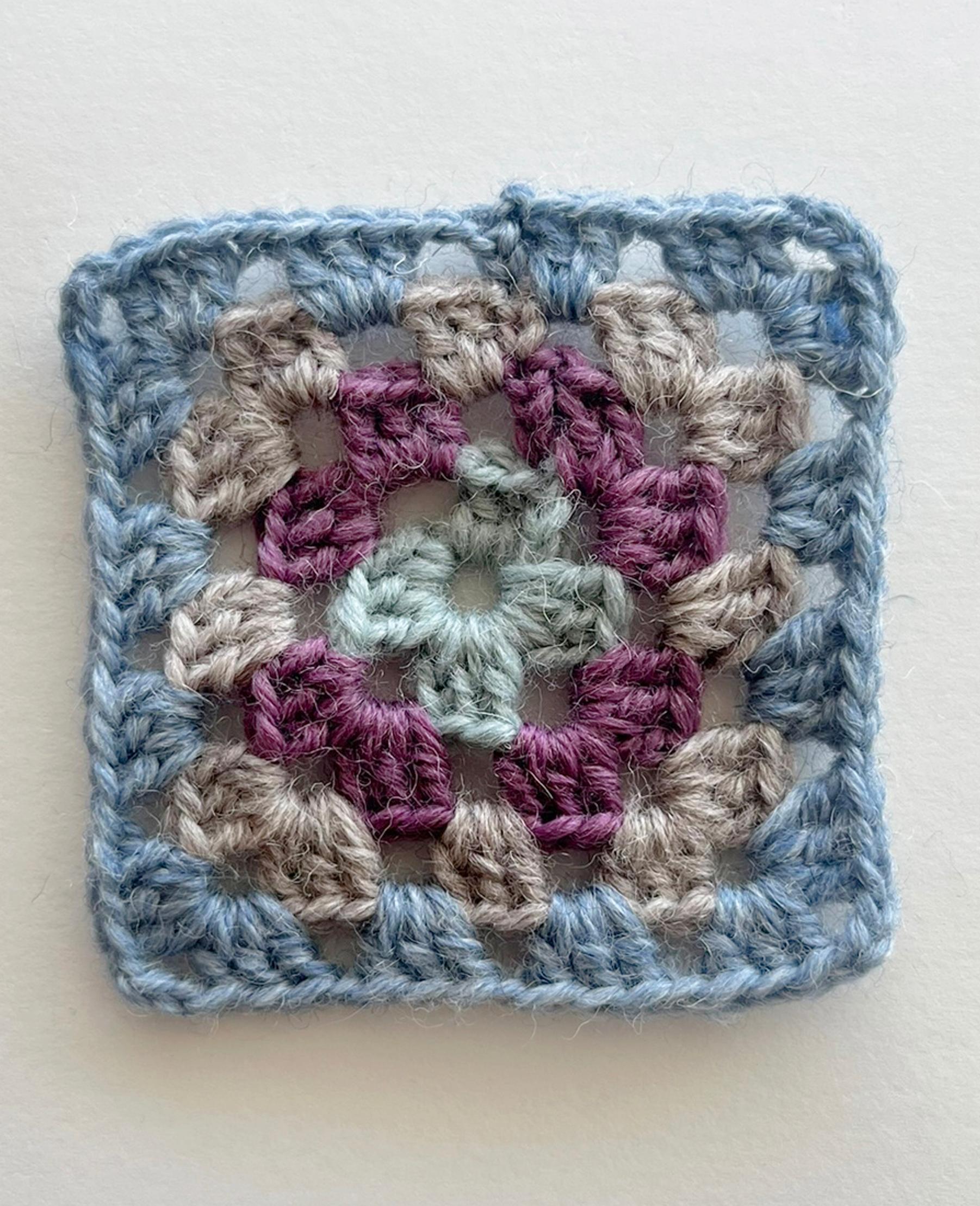 The fourth double-crochet round of the granny square is complete