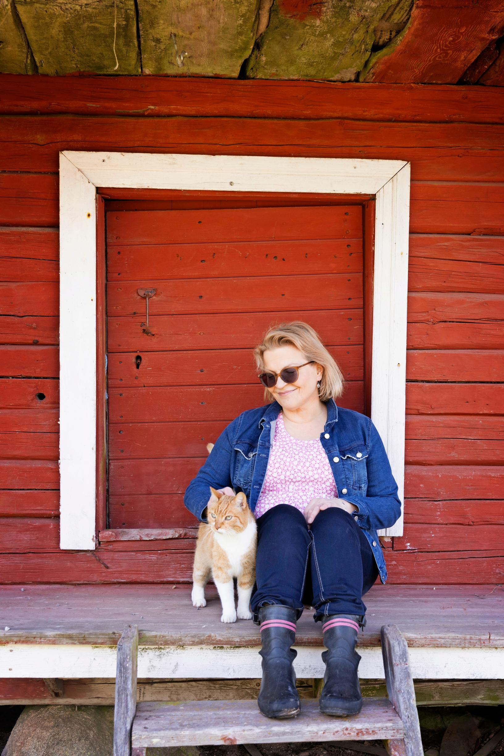 Author Anu Joenpolvi and a cat in their home yard
