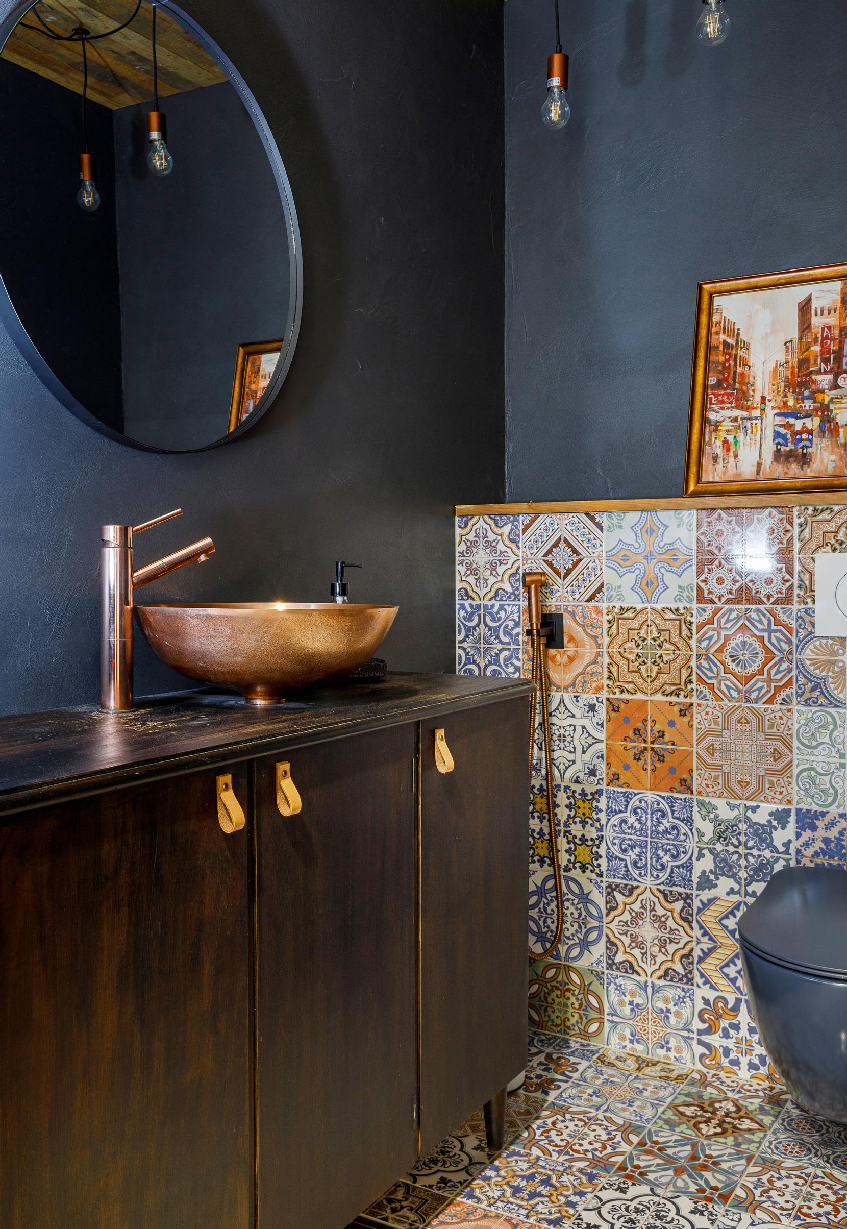 Oriental mosaic tiles and a wall rendered in blue in the toilet.