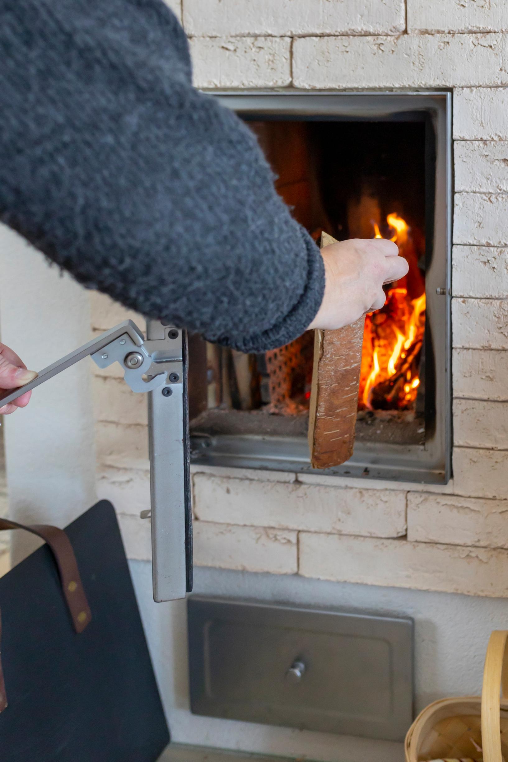 A hand adding wood to the fireplace