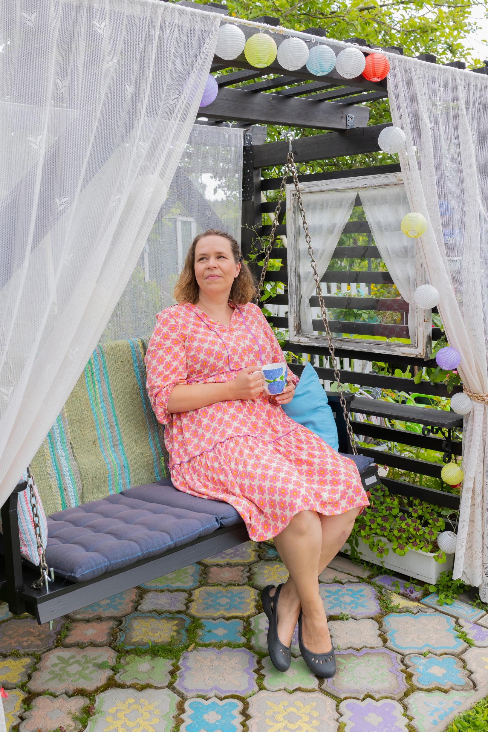 Leni Joutsjoki sitting with a mug in hand on a garden swing