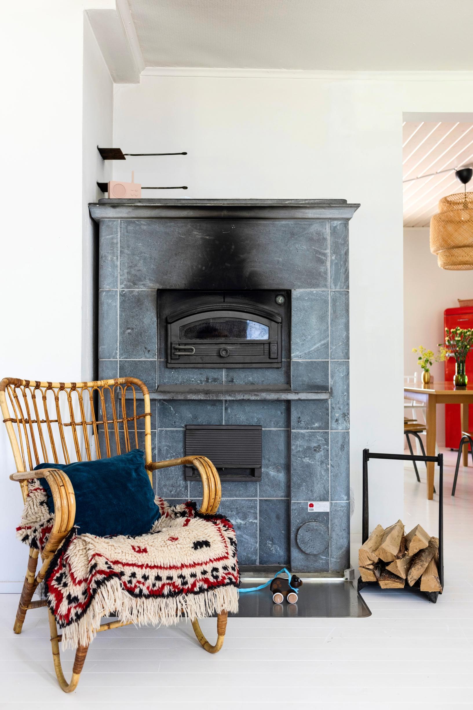 A rattan chair in front of the soapstone fireplace