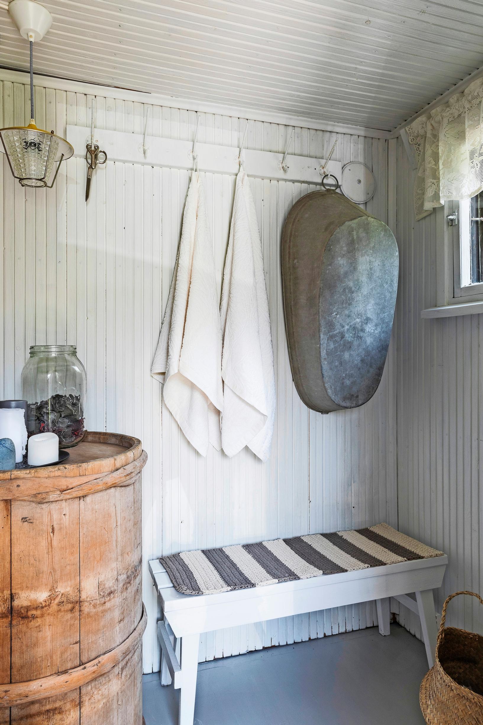 A white-painted paneled changing room with a tub hanging on the coat rack