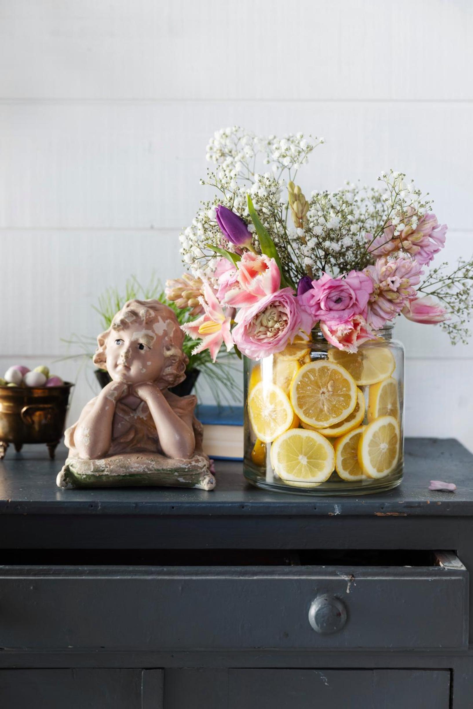 A flower bouquet in a vase filled with lemon slices.