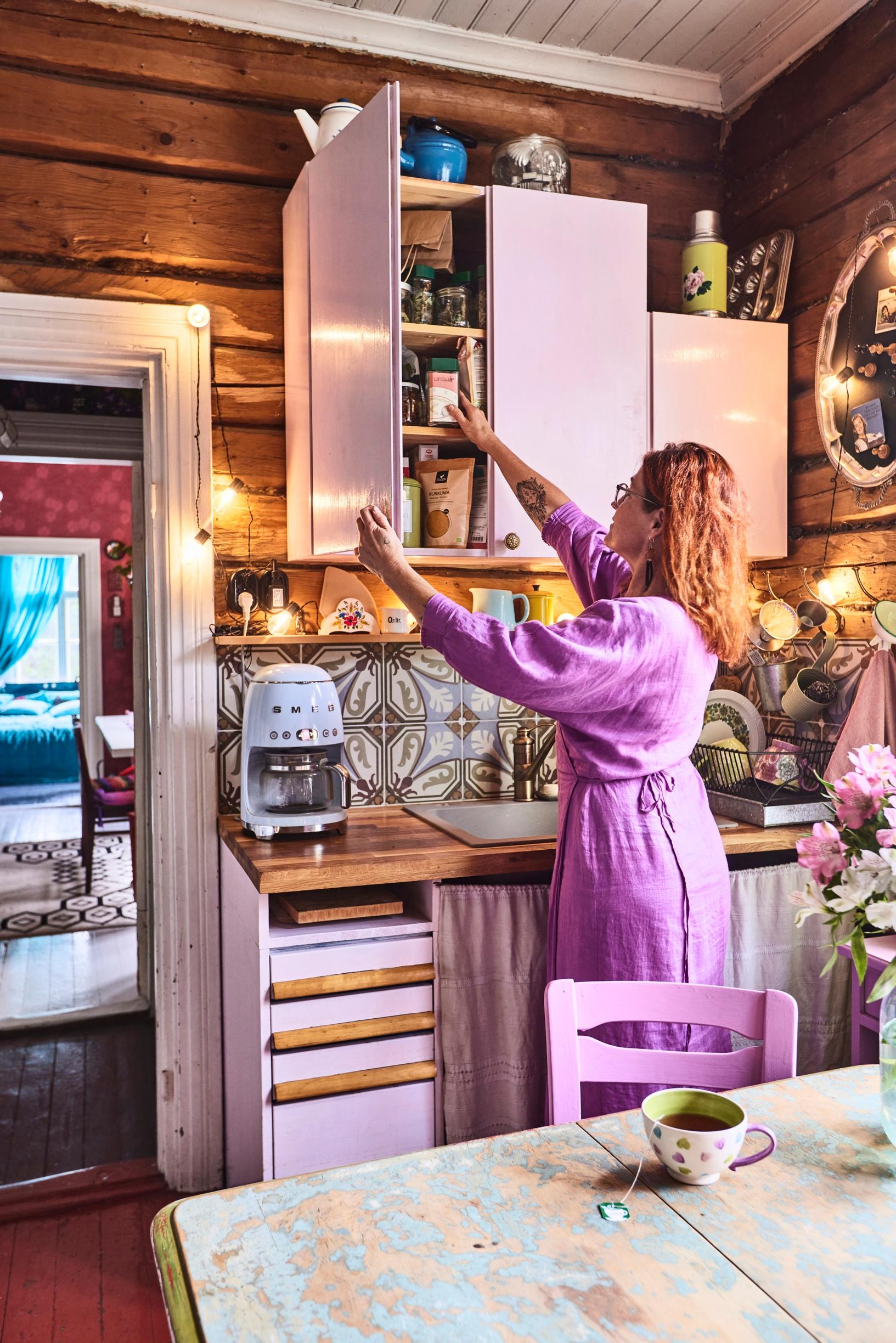 Arja Heinilä taking dishes from the cabinet