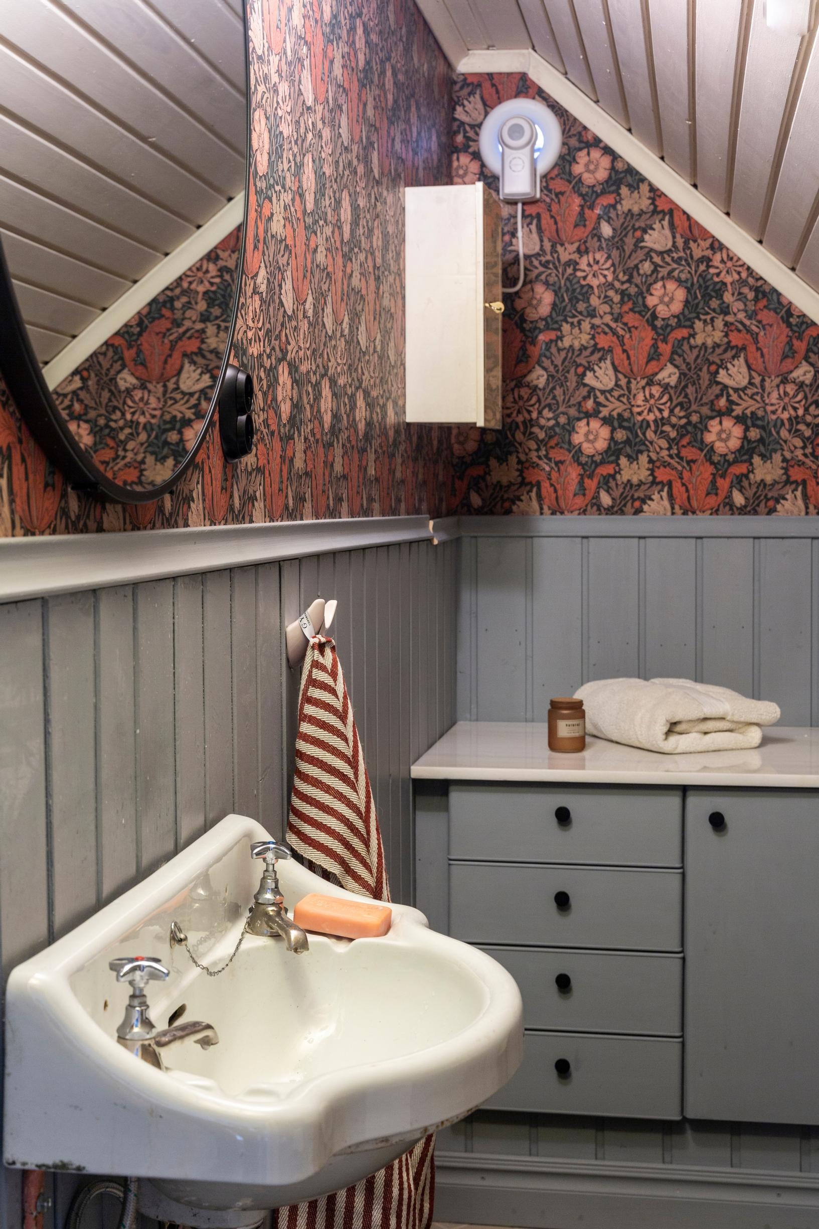 The upstairs bathroom was built under the attic slope and papered with William Morris’s Compton Brown & Orange.