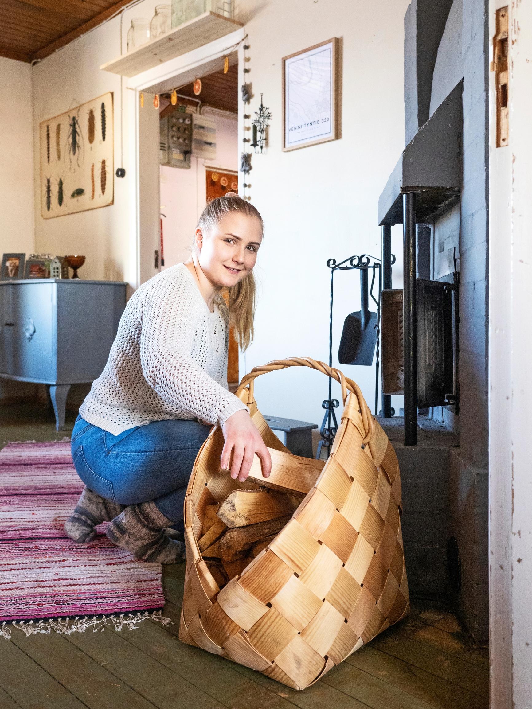 A woman placing firewood into a fireplace