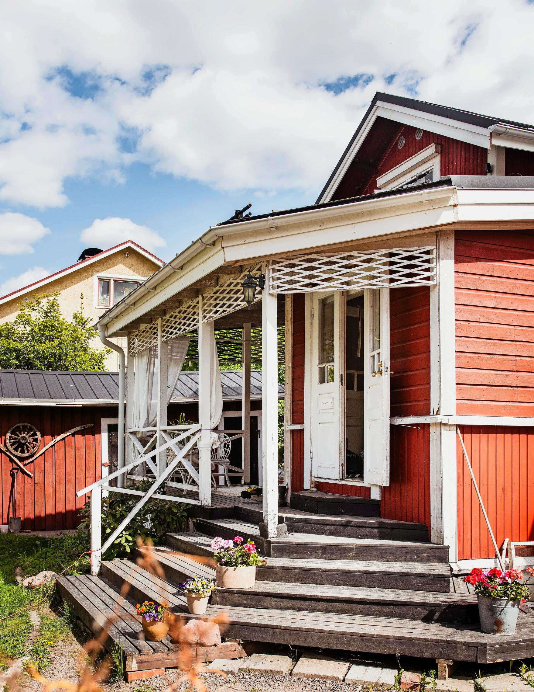 Photo of the porch of the red wooden house.