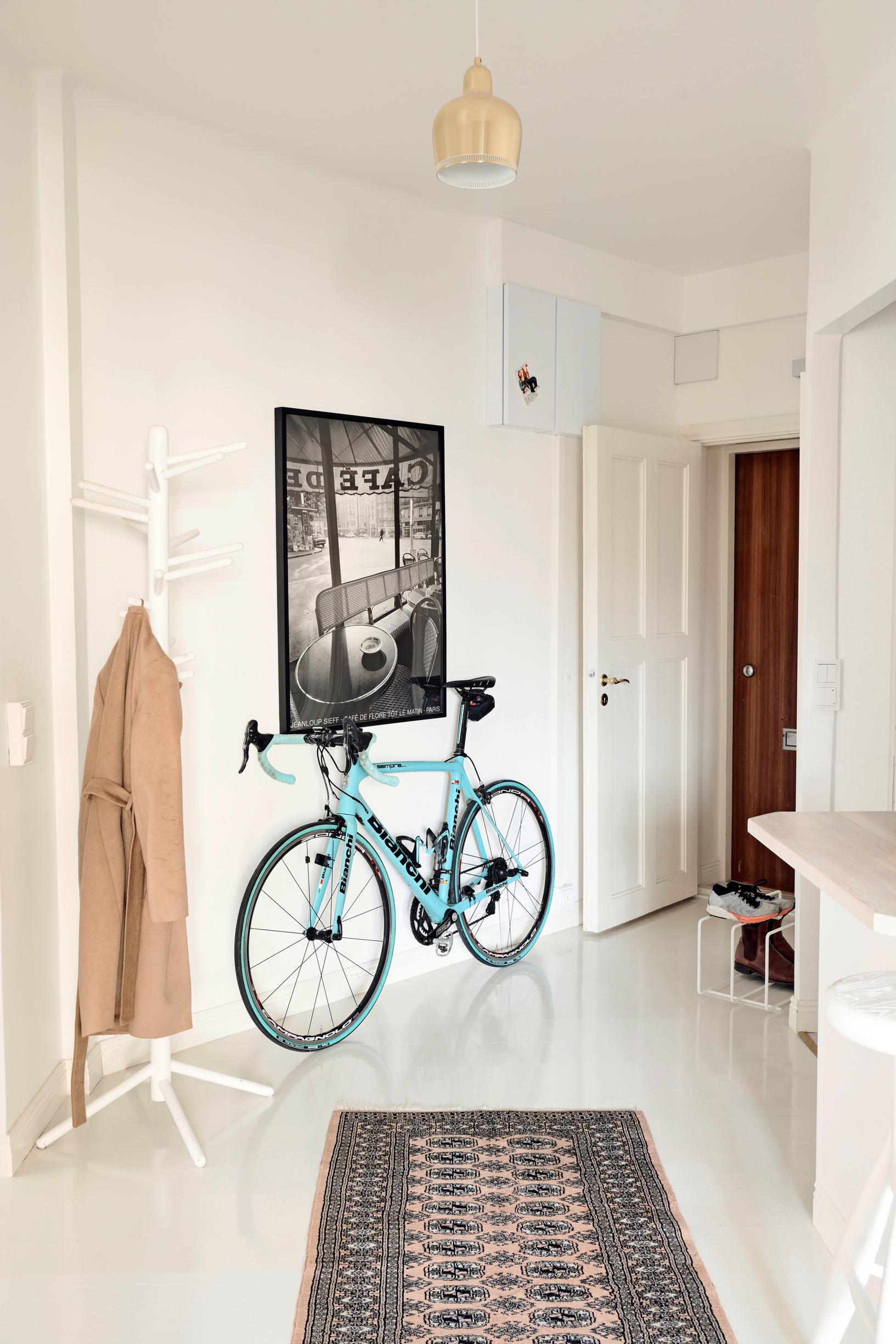 A light blue men's bicycle leaning against the wall in a spacious entryway