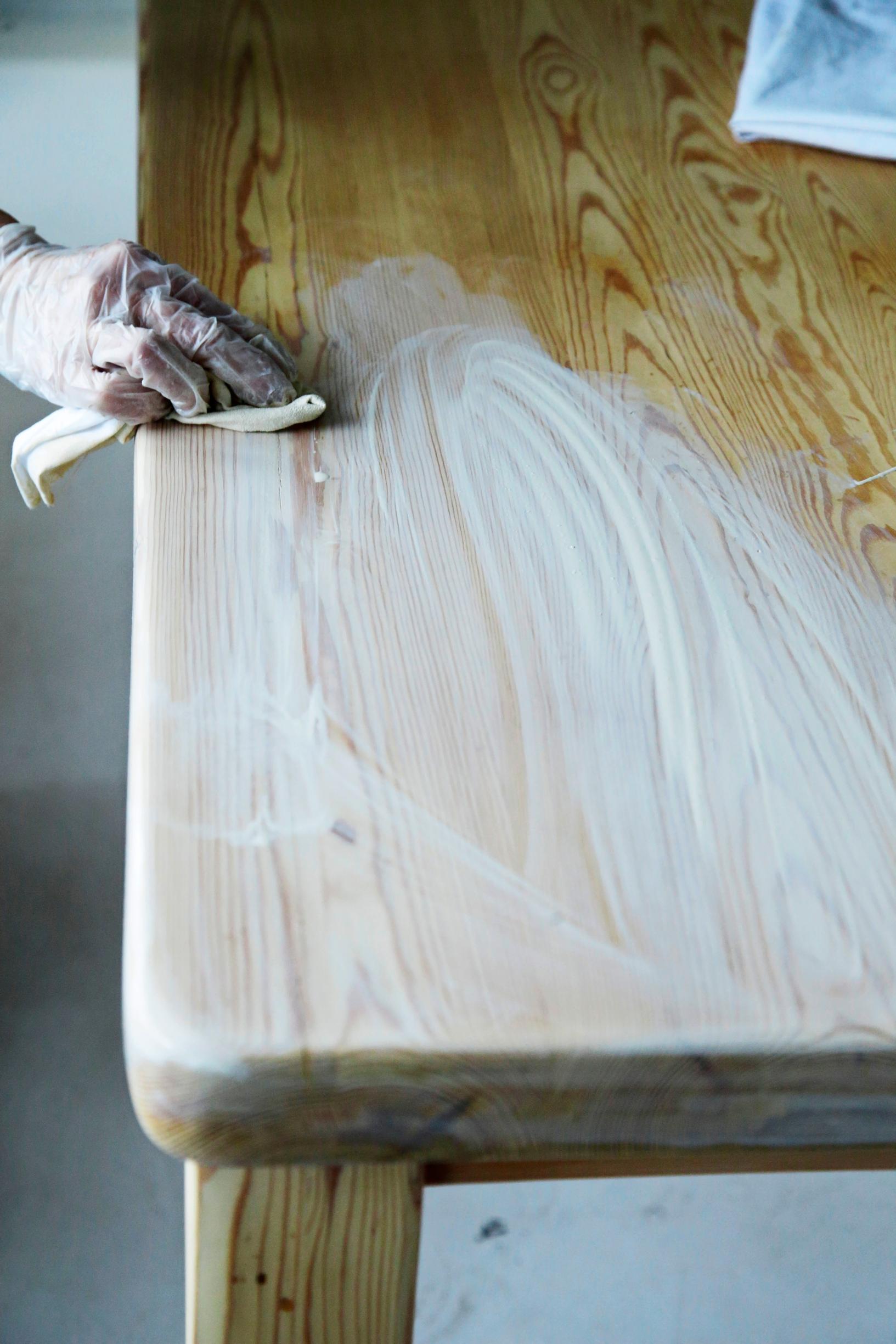 Rubbing wood wax onto the table surface with a cloth