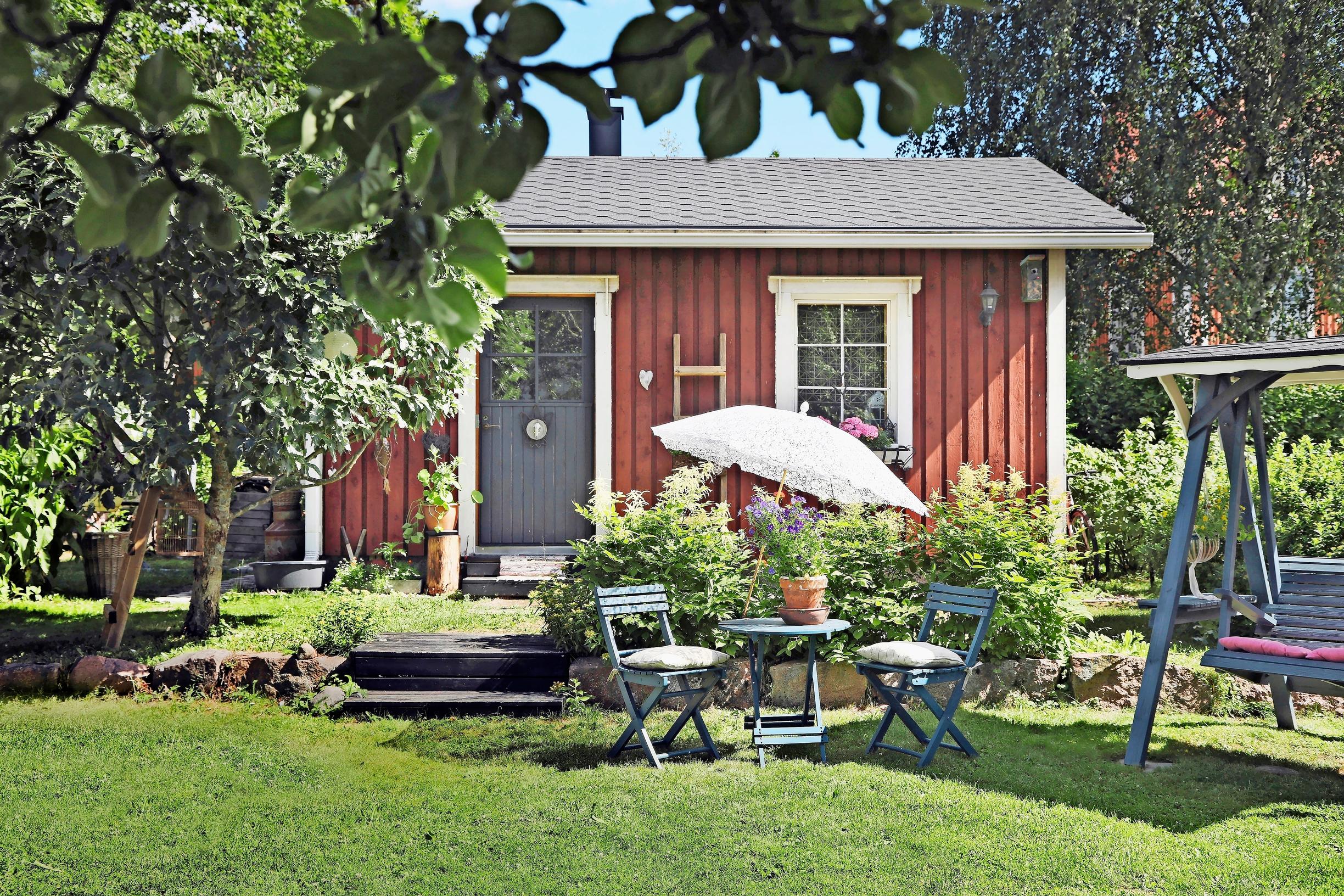 On the lawn, a patio umbrella, folding chairs with pillows, and a small table
