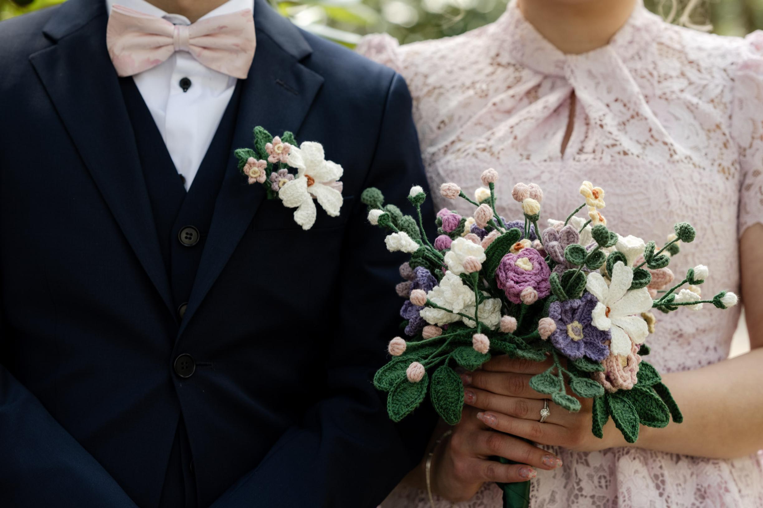 The bride and groom, with the bride holding the crocheted bouquet.