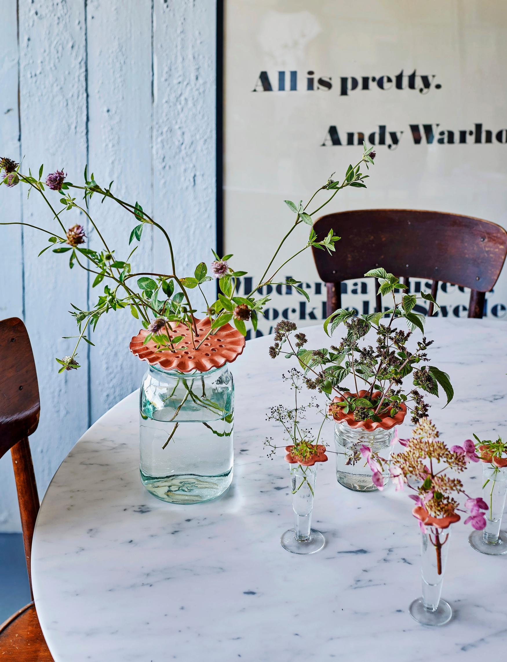 Flower supports made from air-dry clay on both a vase and a shot glass.