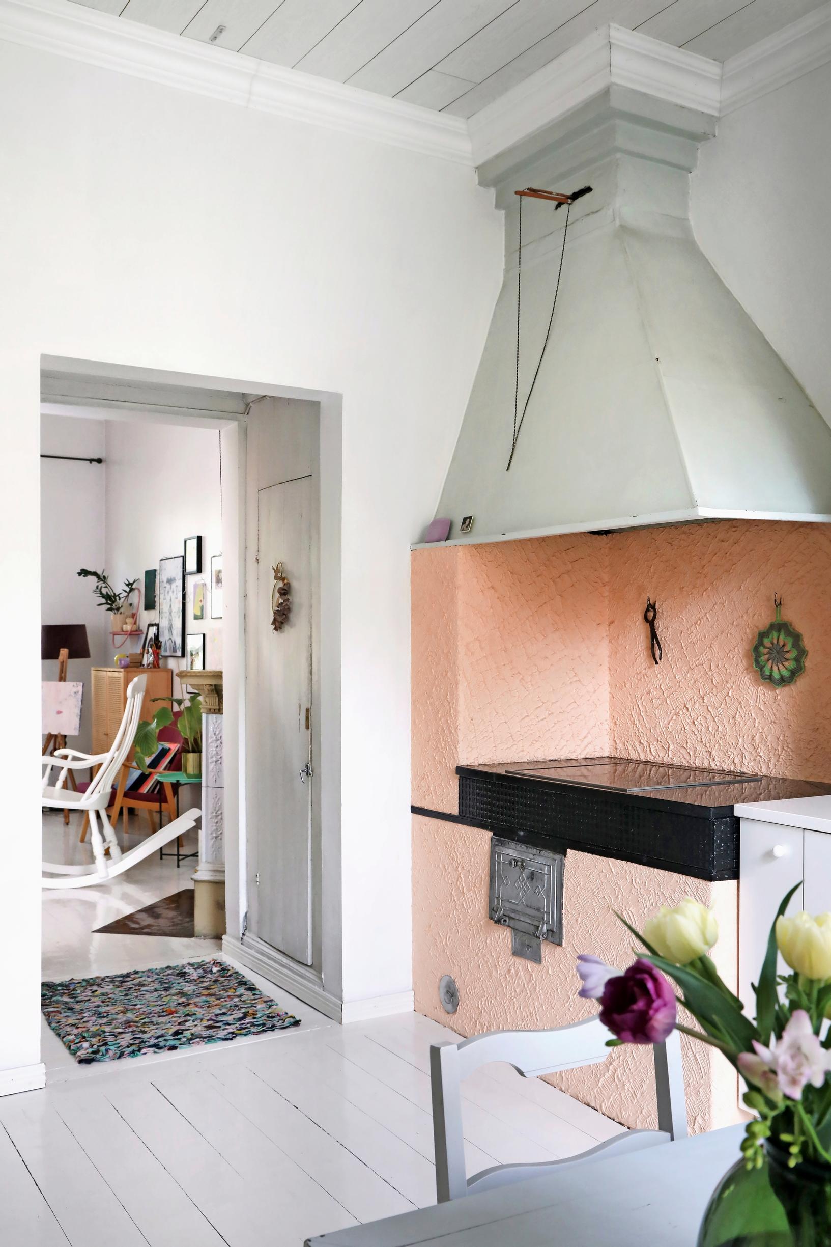 A photo of the pink-painted wood-burning stove in the kitchen of an old wooden home.