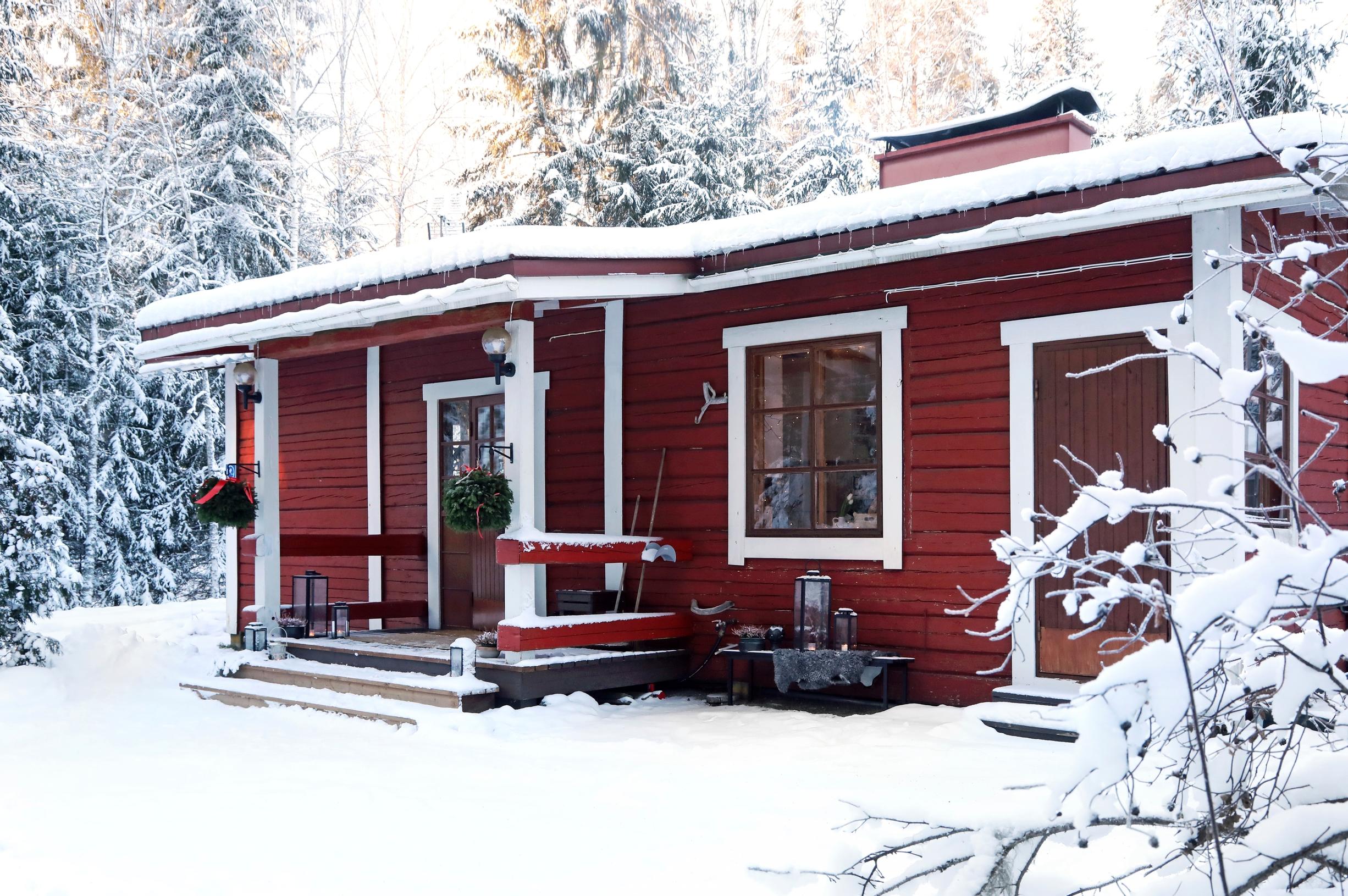 Ulla Parviainen’s red log cabin in Pusula, Lohja, with snowy woods in the background.