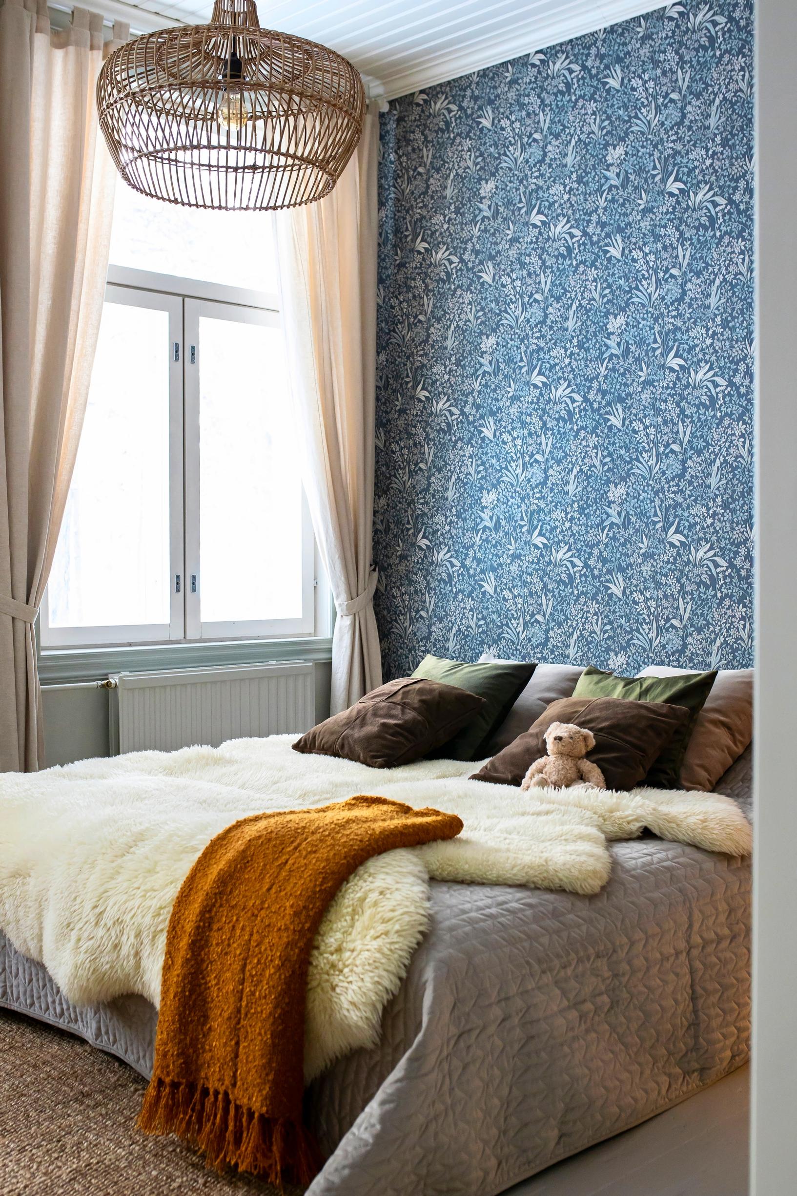 The guest room’s walls are decorated with blue-toned floral wallpaper