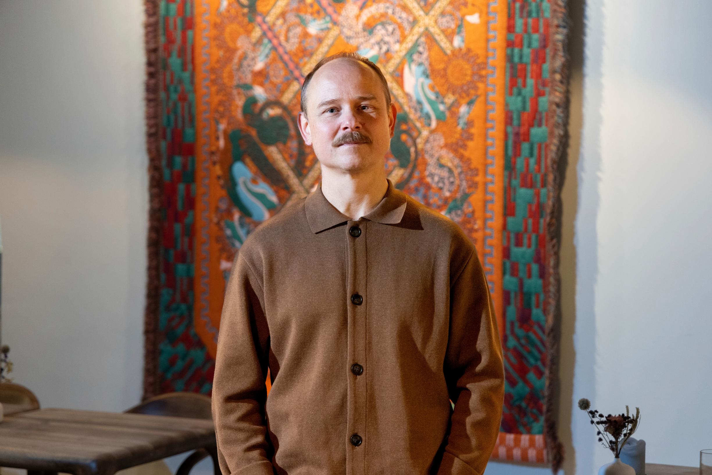 Illustrator Kustaa Saksi in front of his textile artwork