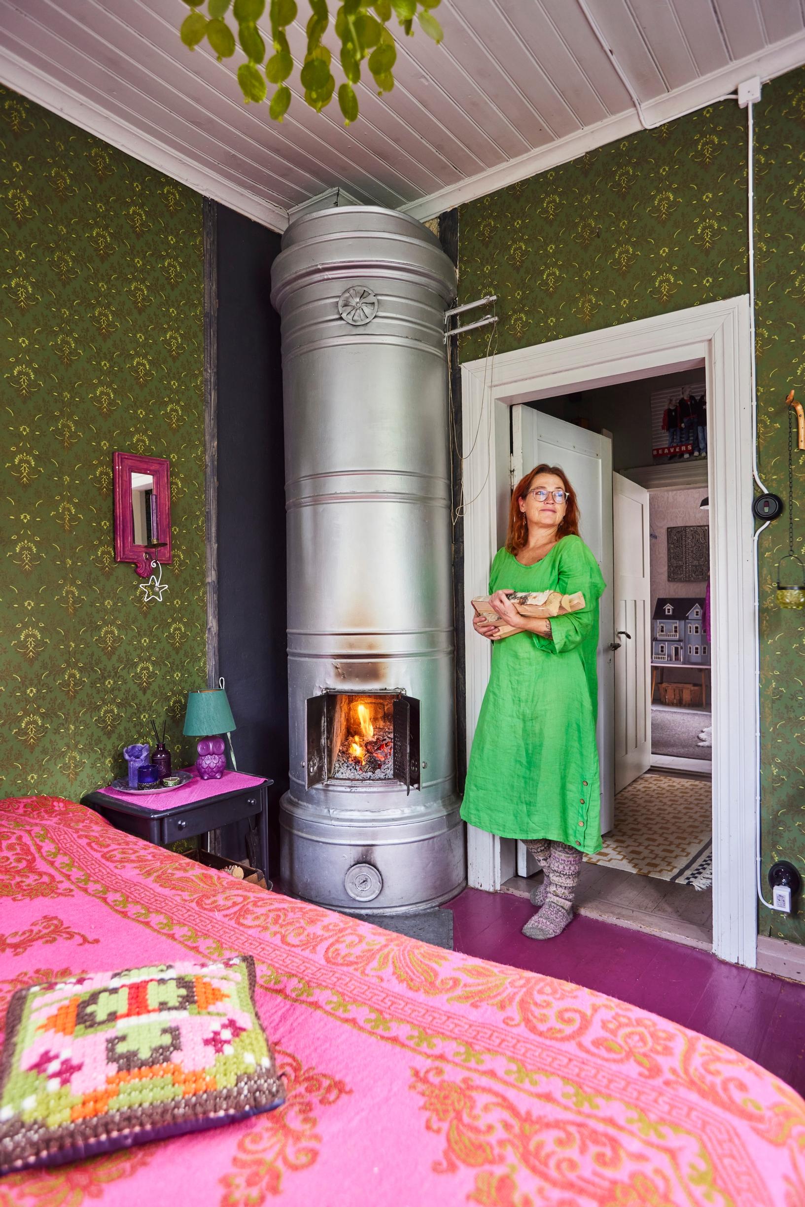 Arja Heinilä bringing wood to an old tiled stove