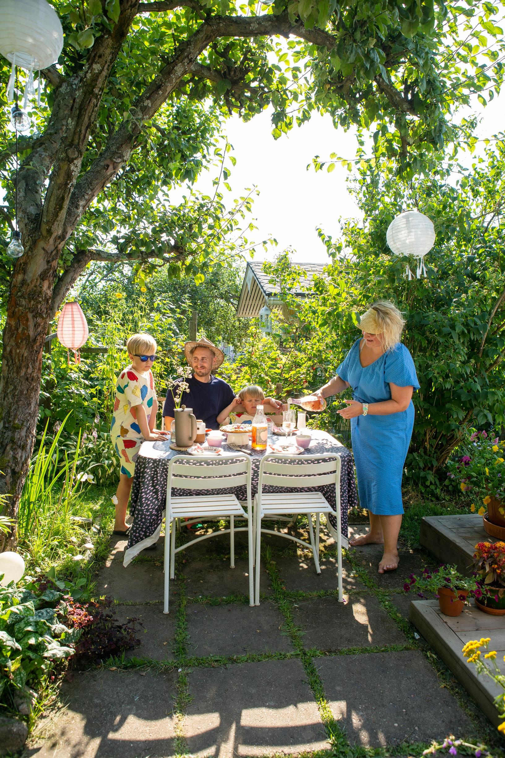 Family sitting at a table in the garden of their community garden cottage