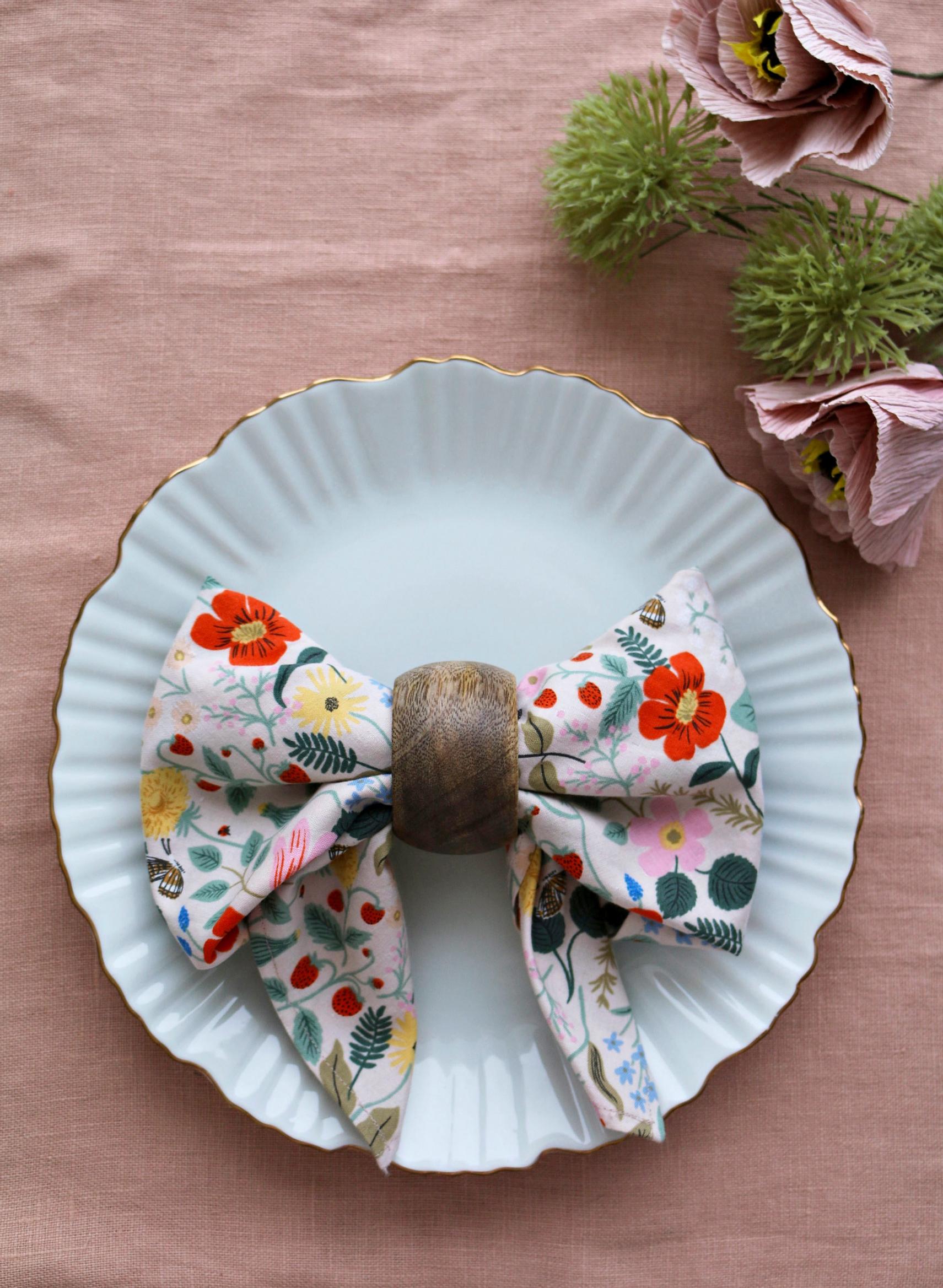 Unfold the napkin on both sides of the ring to create a bow.