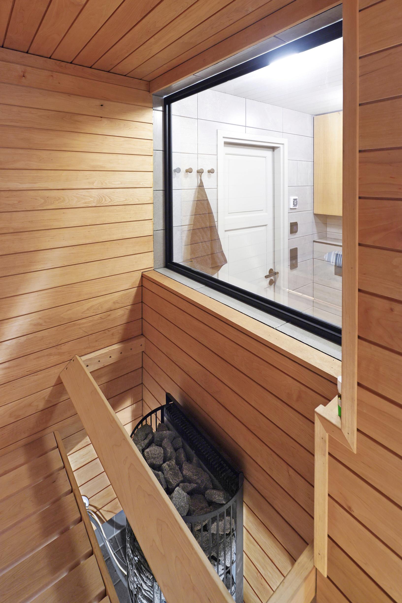 In the sauna, the window above the stove provides a view of the bathroom door.