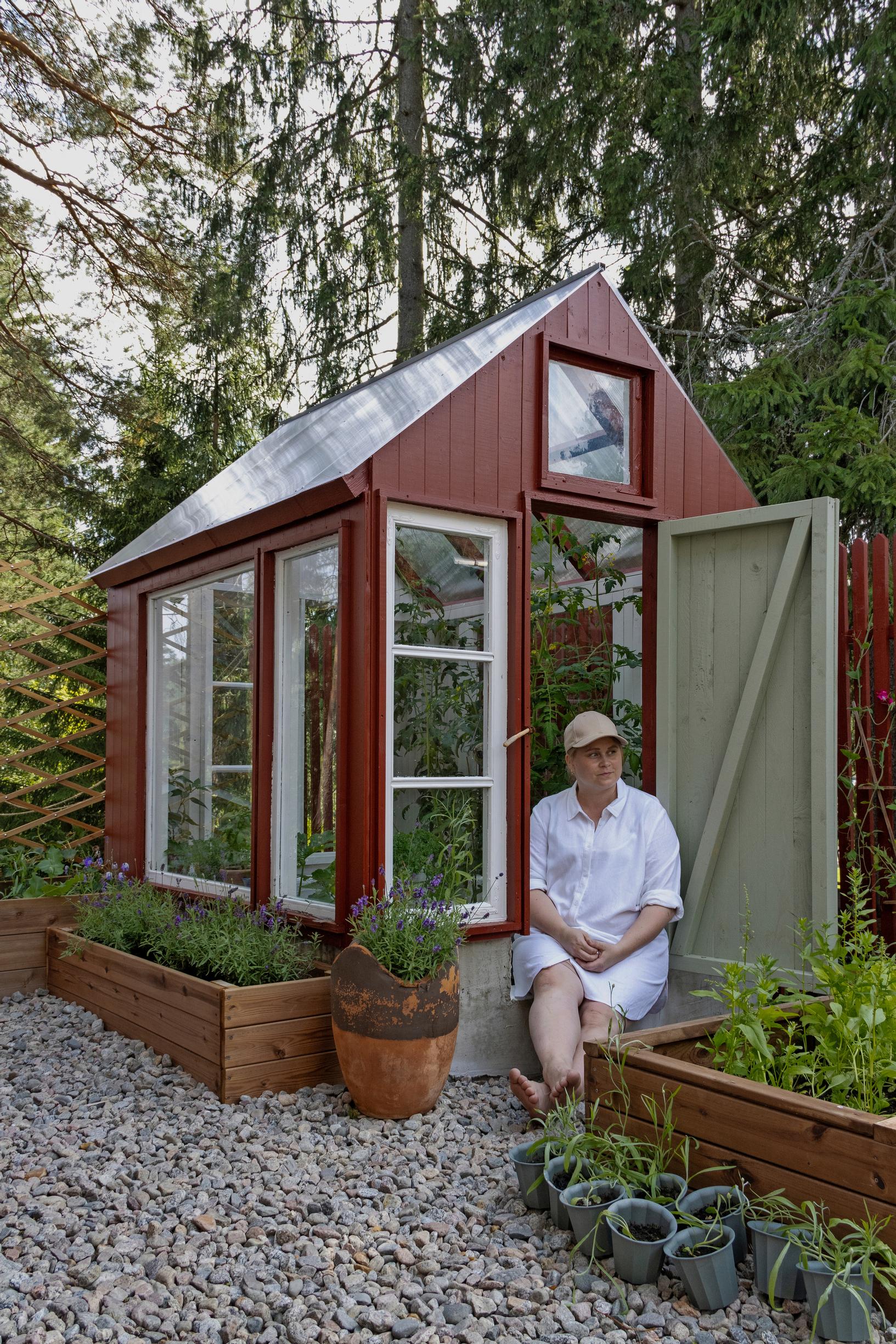 Rilla Tervonen sits in the doorway of the greenhouse.