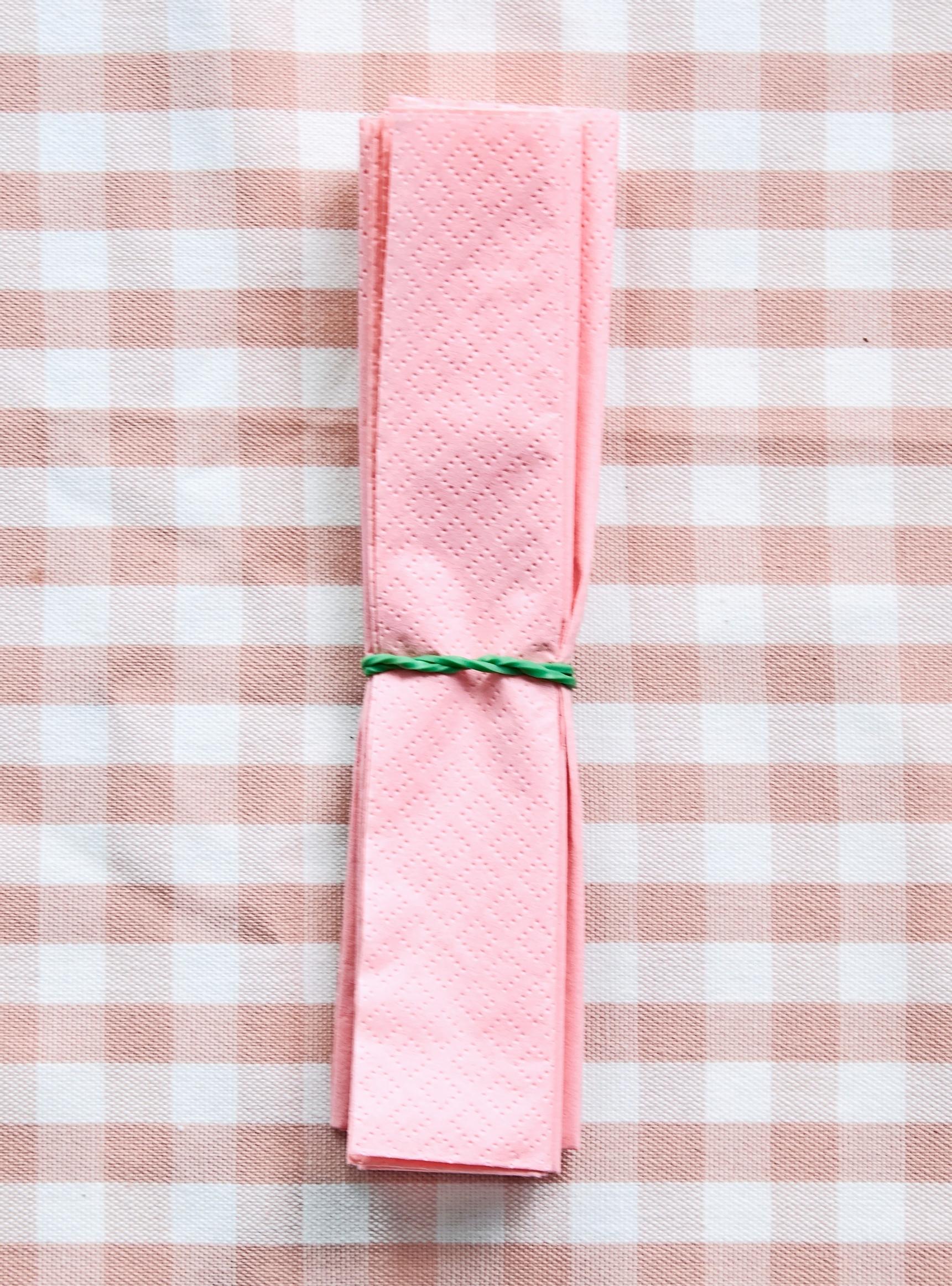A rubber band is placed in the center of the accordion-folded napkin.