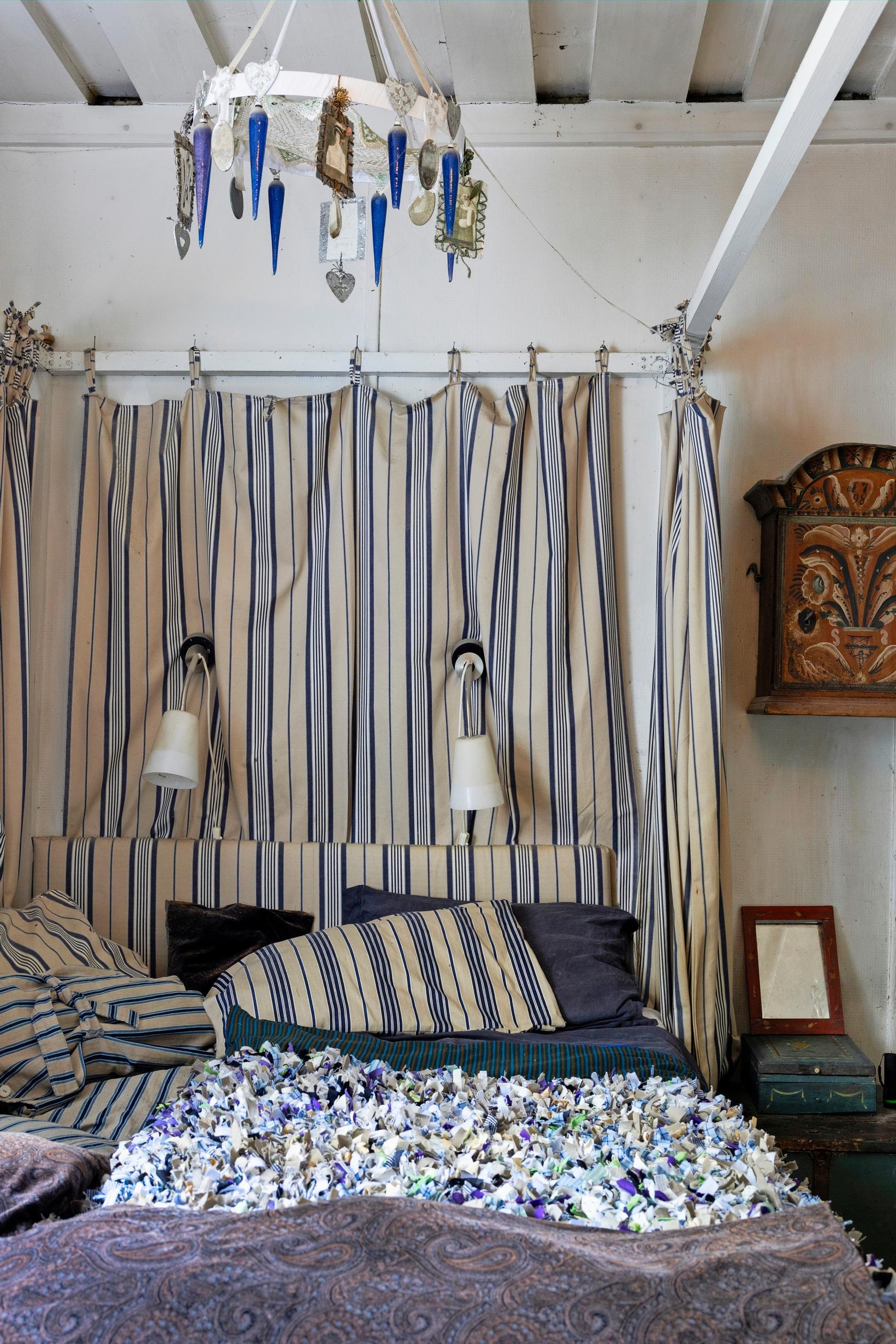 A bed with striped fabric hung at the headboard.