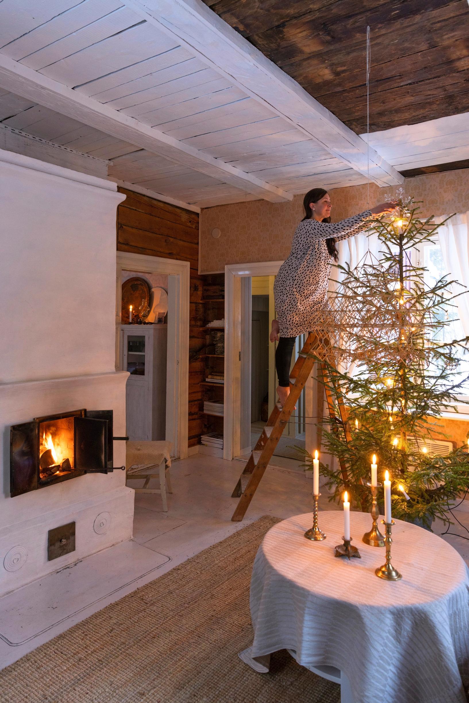 Minni decorating the tree using a ladder.