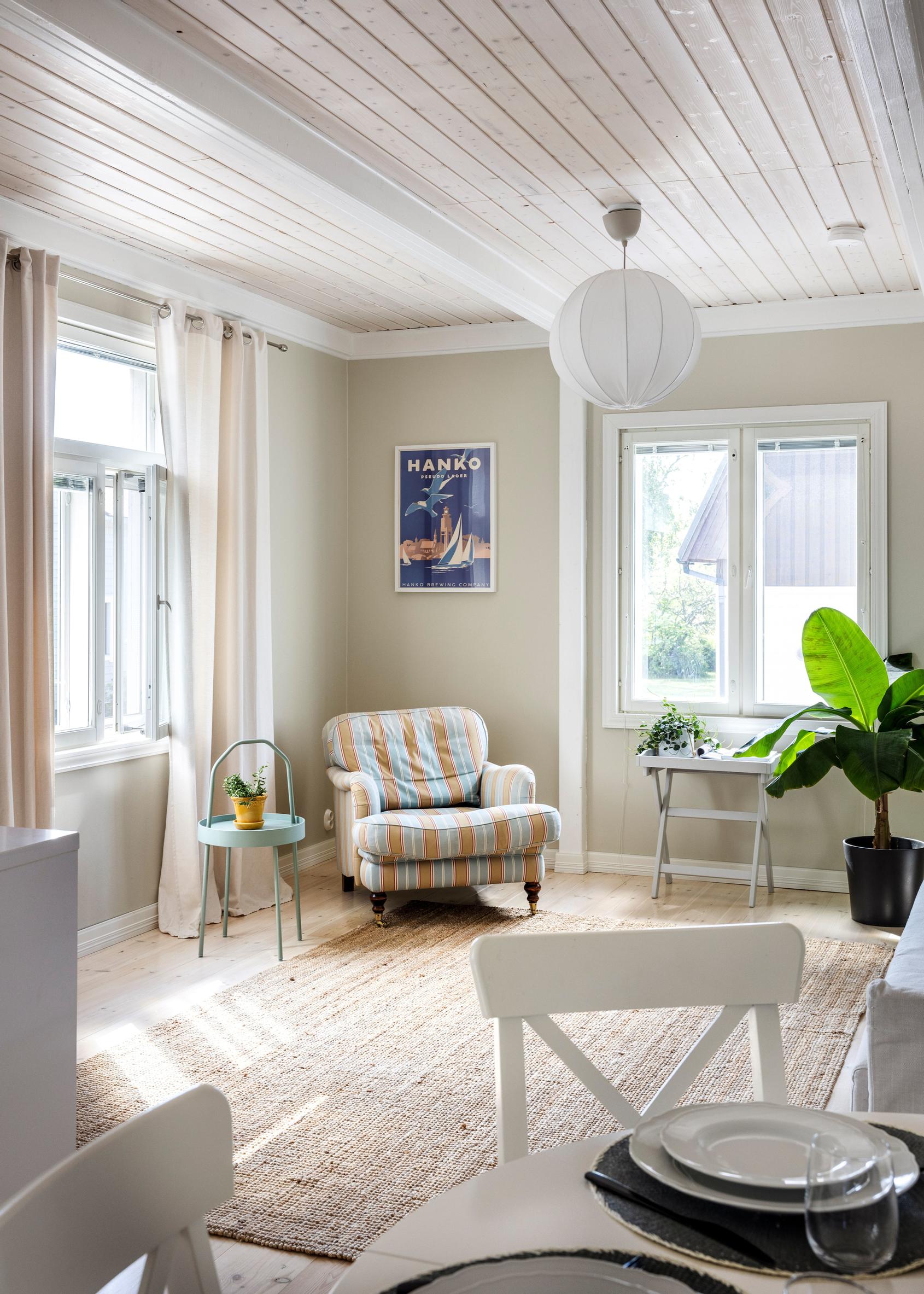 The living room has light brown walls and a striped armchair.