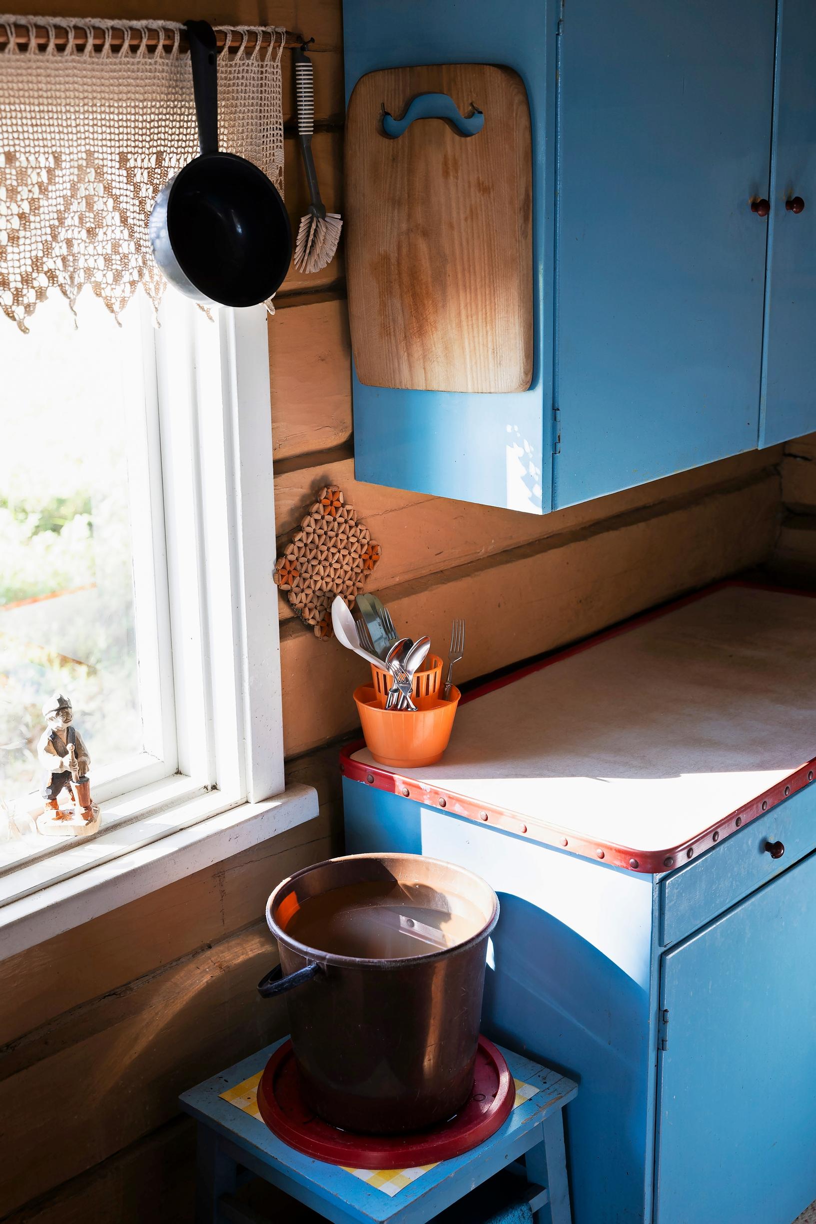 Blue kitchen cabinets and a water bucket on a stool