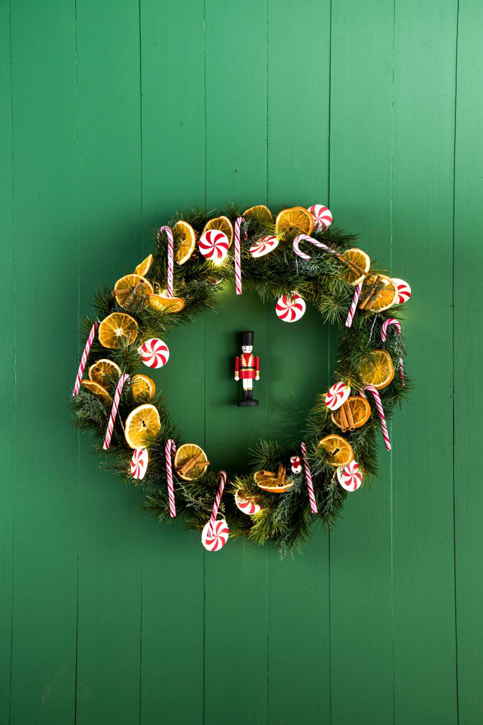 An everlasting wreath decorated with dried orange slices, cinnamon sticks, candy canes, and string lights.
