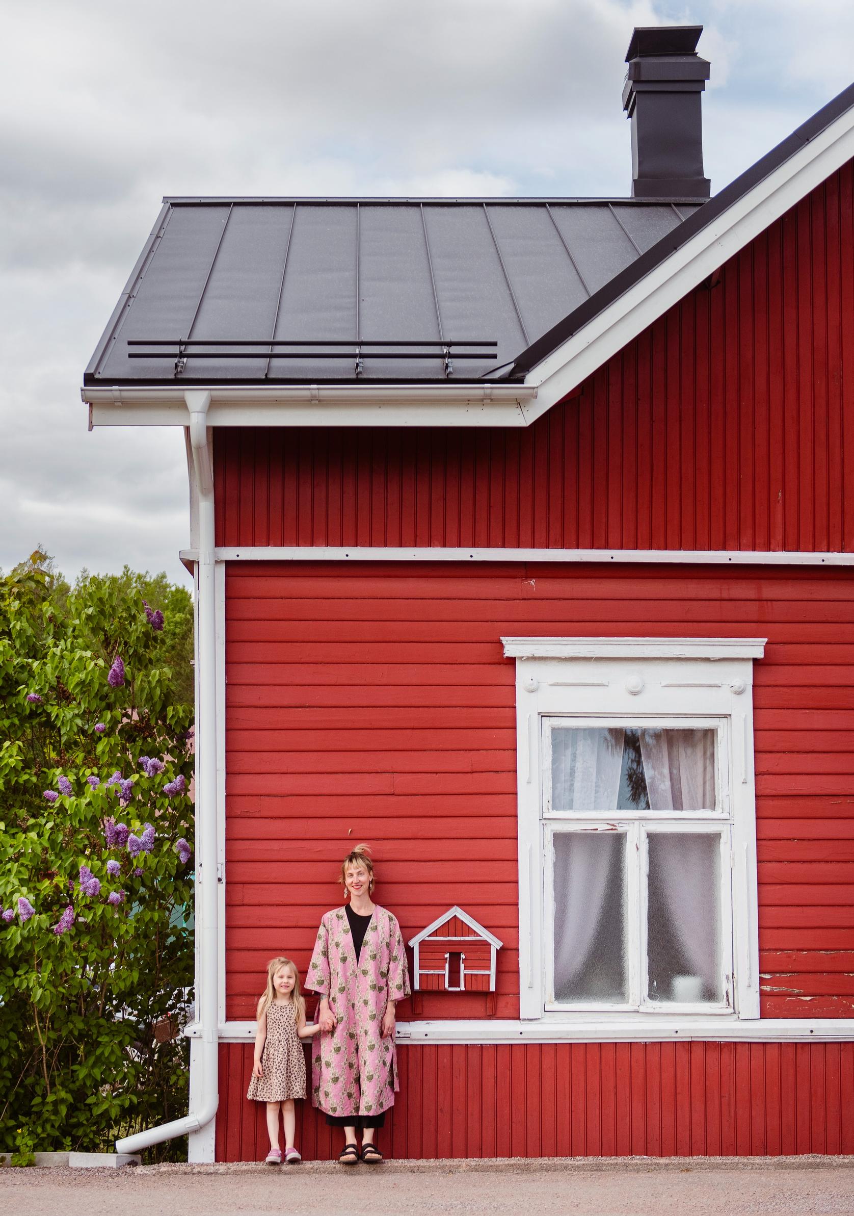 Photo of mother and daughter in front of a red wooden house in Loviisa.