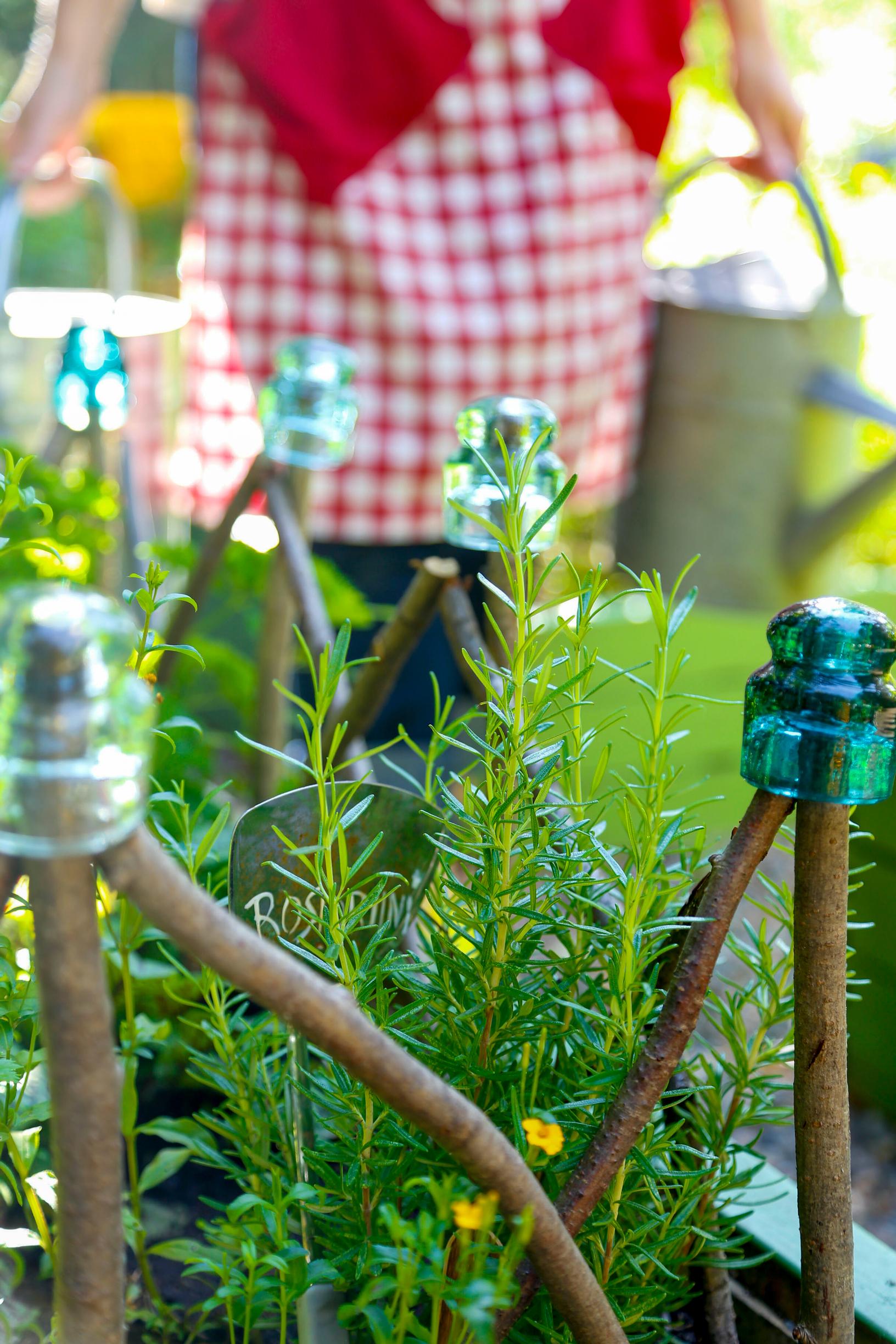 Old glass insulators decorate the tips of a branch fence.