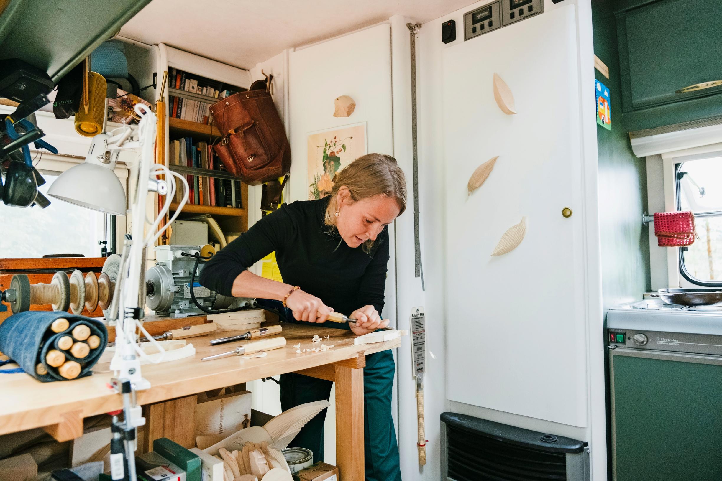 woman carving wood at a workbench