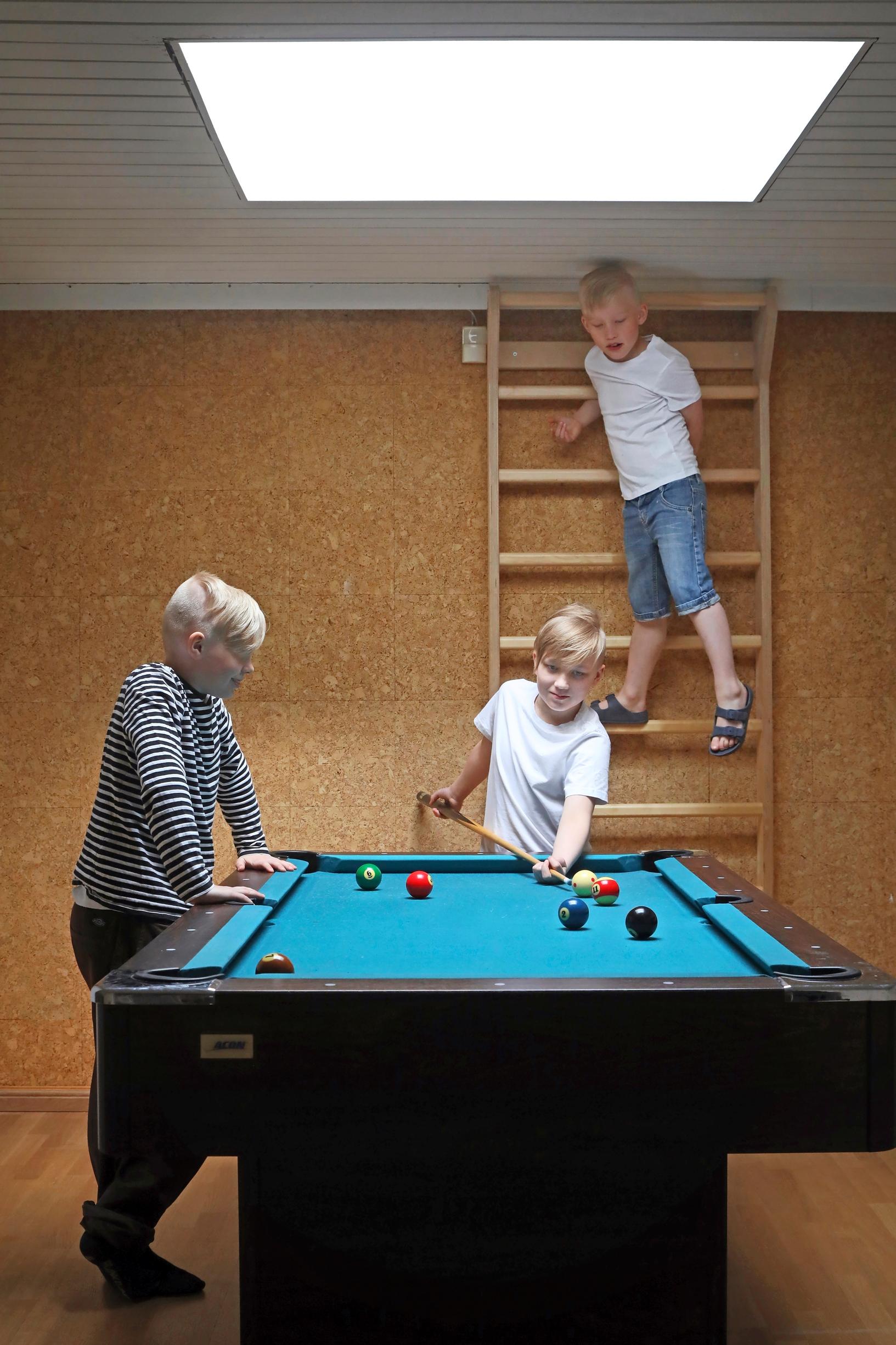 Photo of children playing pool and climbing on wall bars.