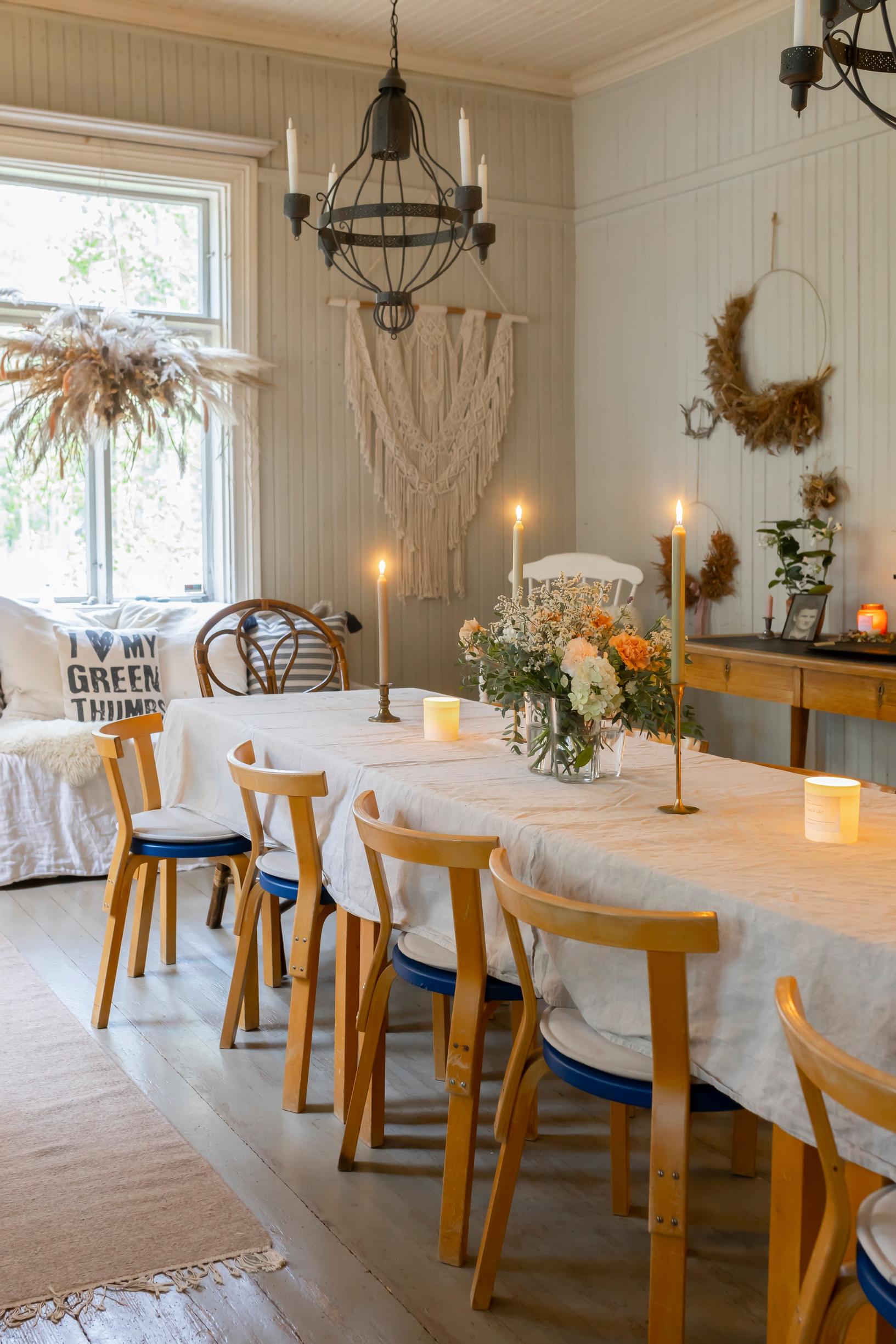 A long table with at least ten chairs, white tablecloth, and candles.