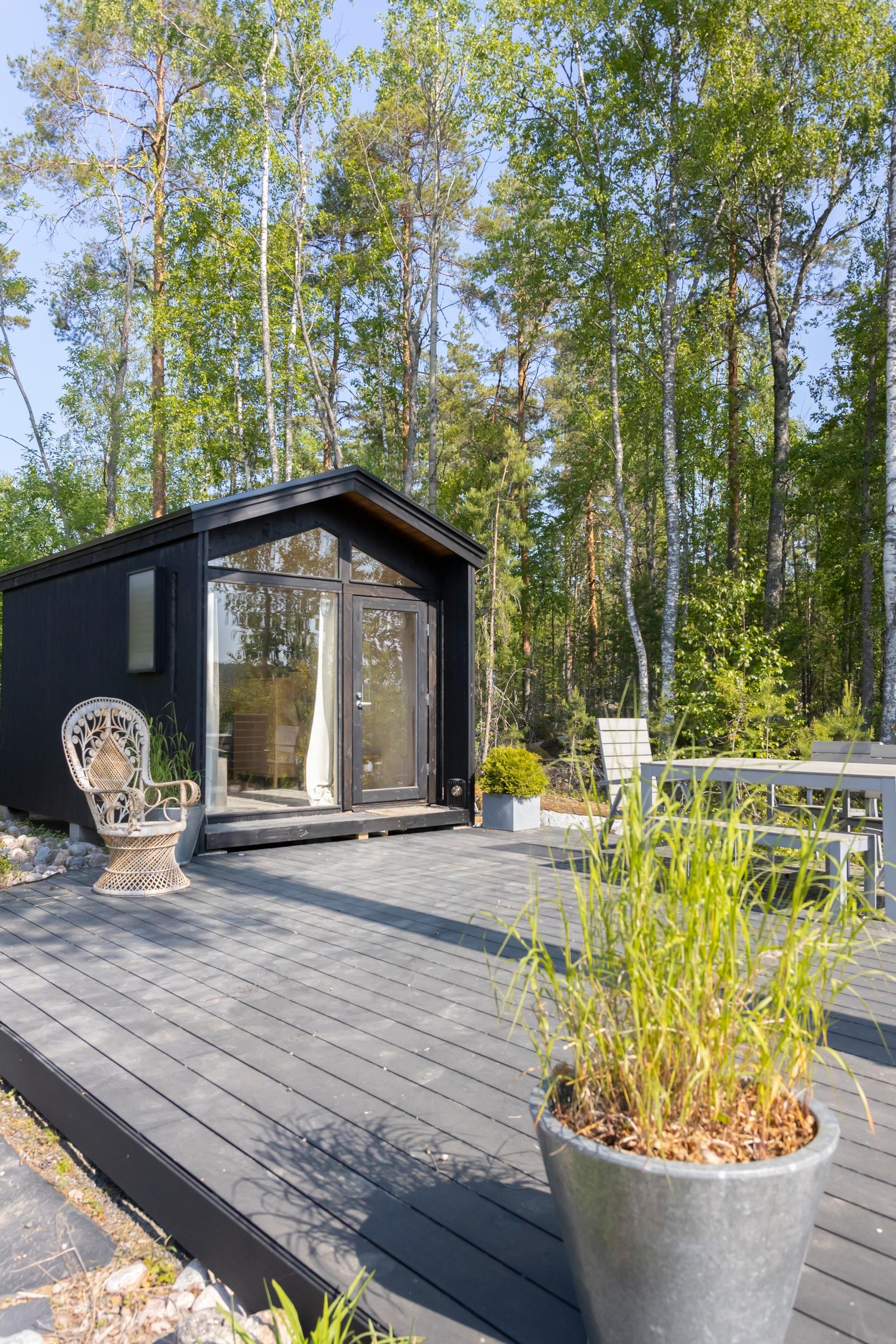 a small black cabin, a rattan chair, terrace space, and a plant in a pot