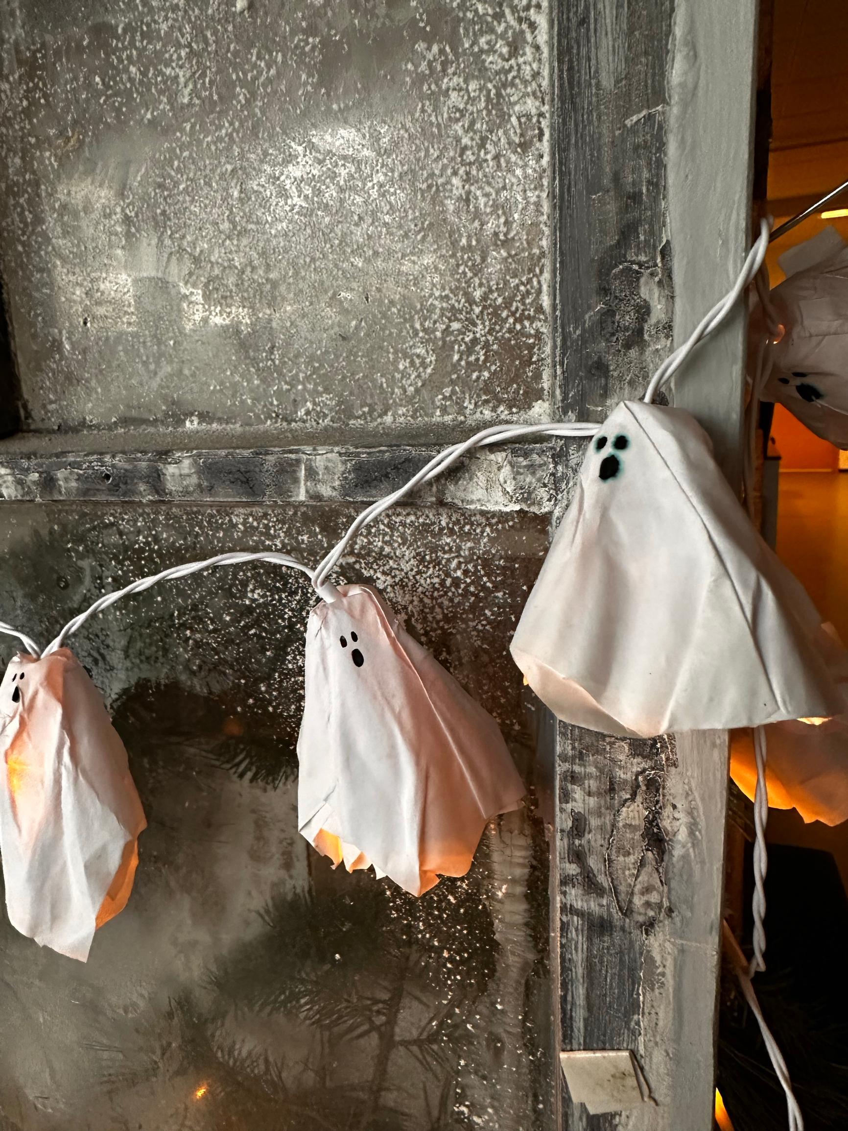 Ghost-shaped lights or a light string made of copy paper in a window.