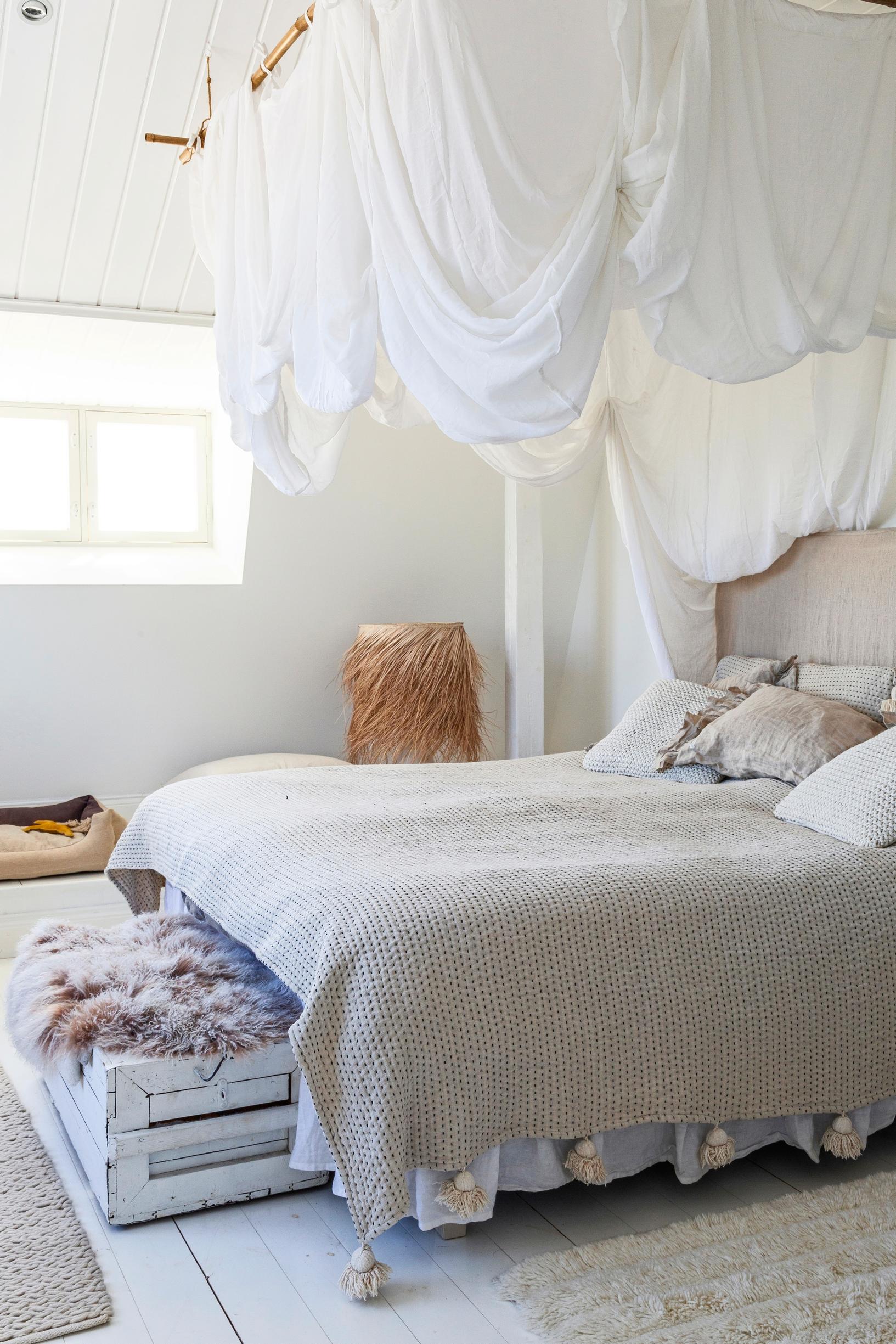 Bright bedroom with a bed canopy and linen sheets