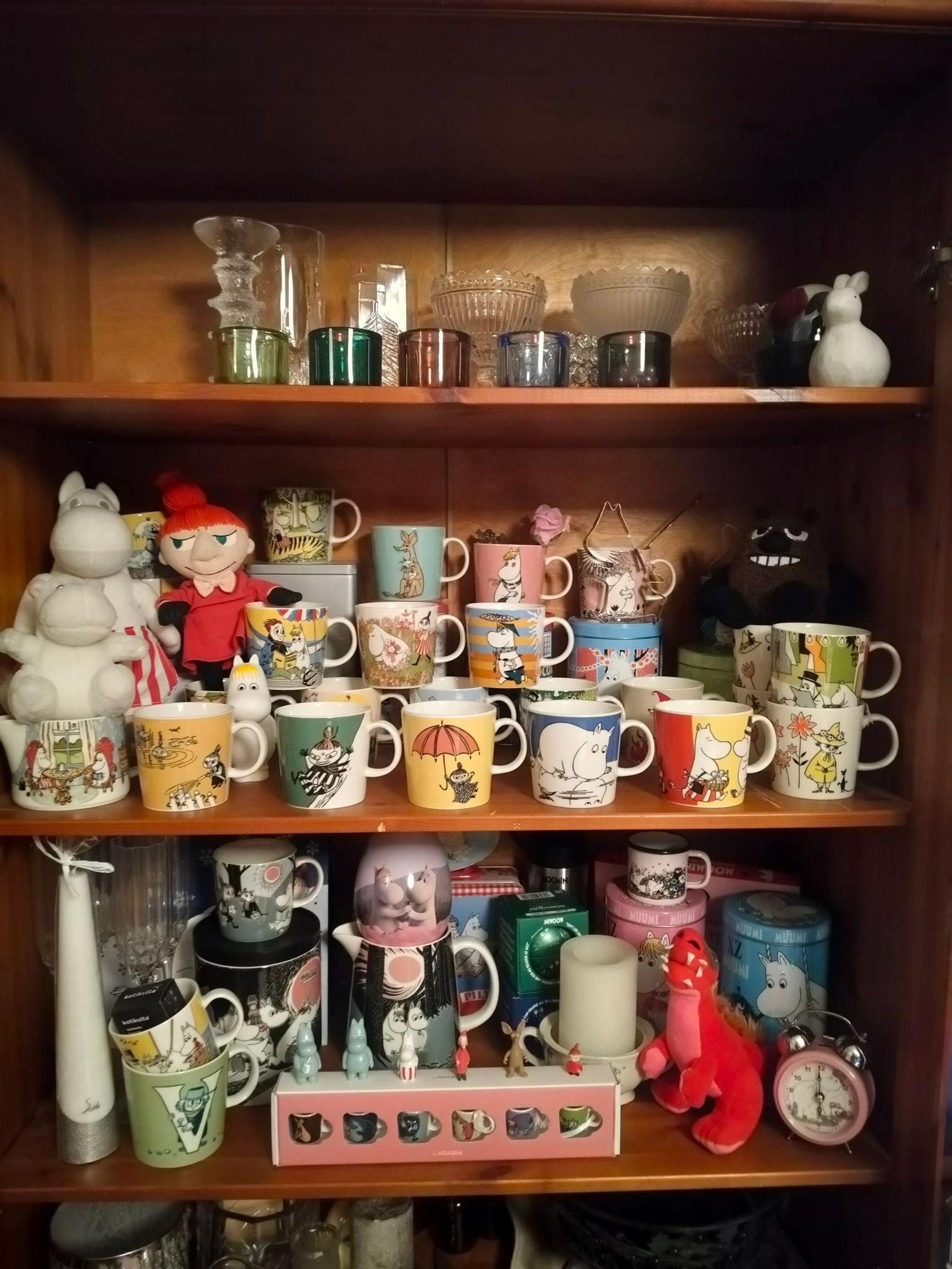 Virve Kauppi’s Moomin mugs in a wooden cabinet